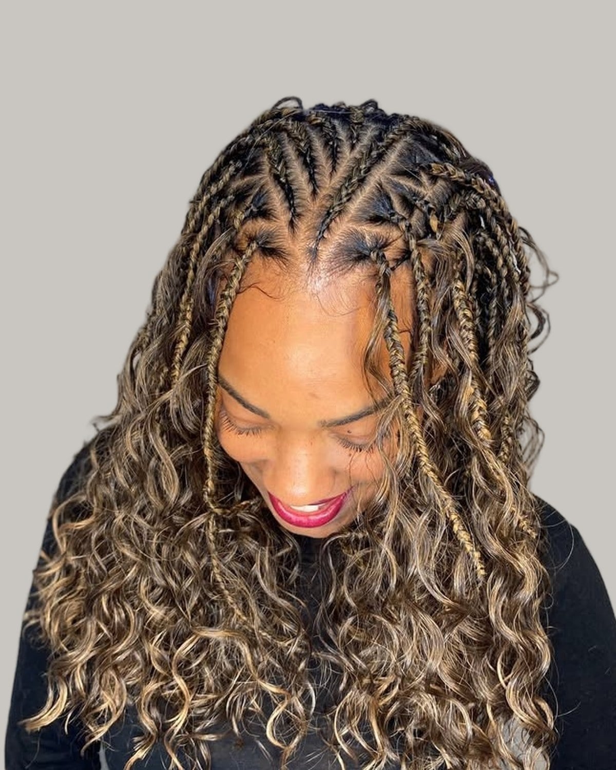 Woman looking down with flip-over Fulani braids, brown with blonde highlights and curls