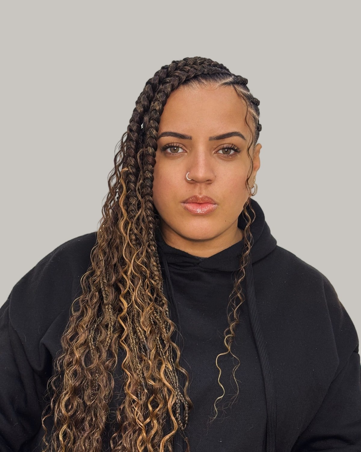 Woman in a black hoodie with Fulani braids, honey streaks and curly pieces