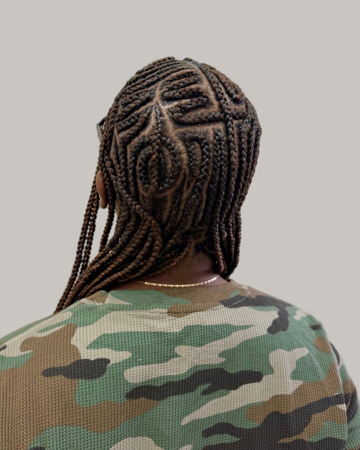 Back view of Fulani braids with swirled and looped cornrows over a camouflage top