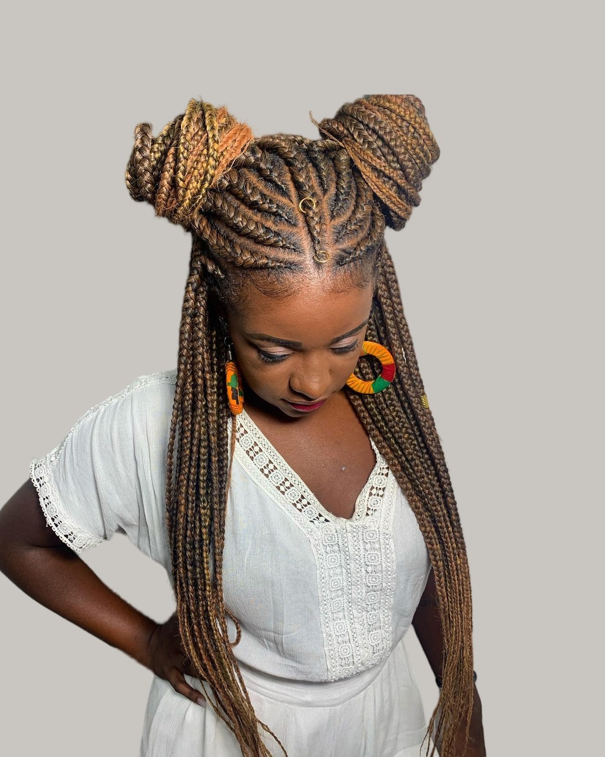 Woman in a white blouse with honey-brown Fulani braids in two space buns