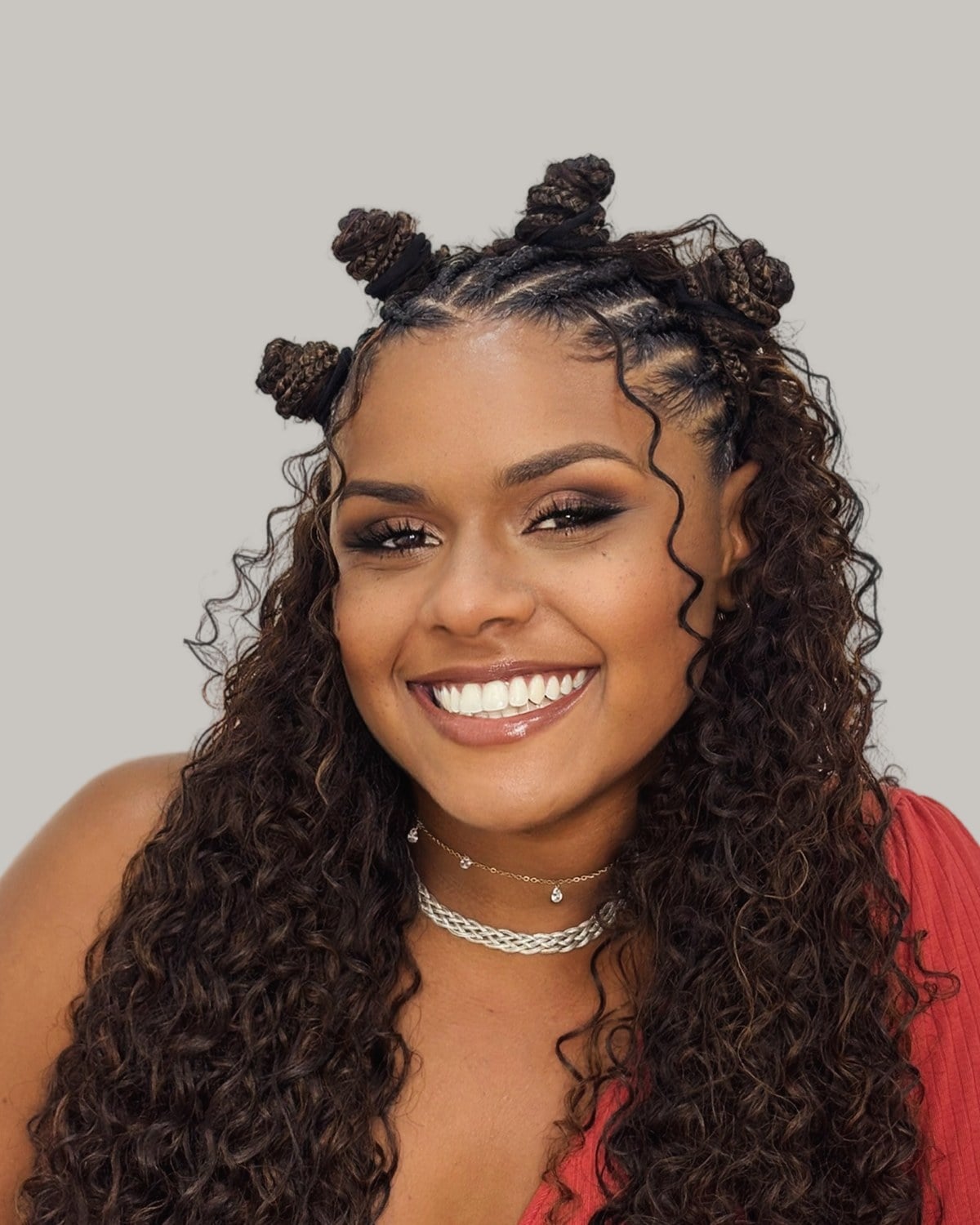 Smiling woman in a red top with small buns on top and long curls
