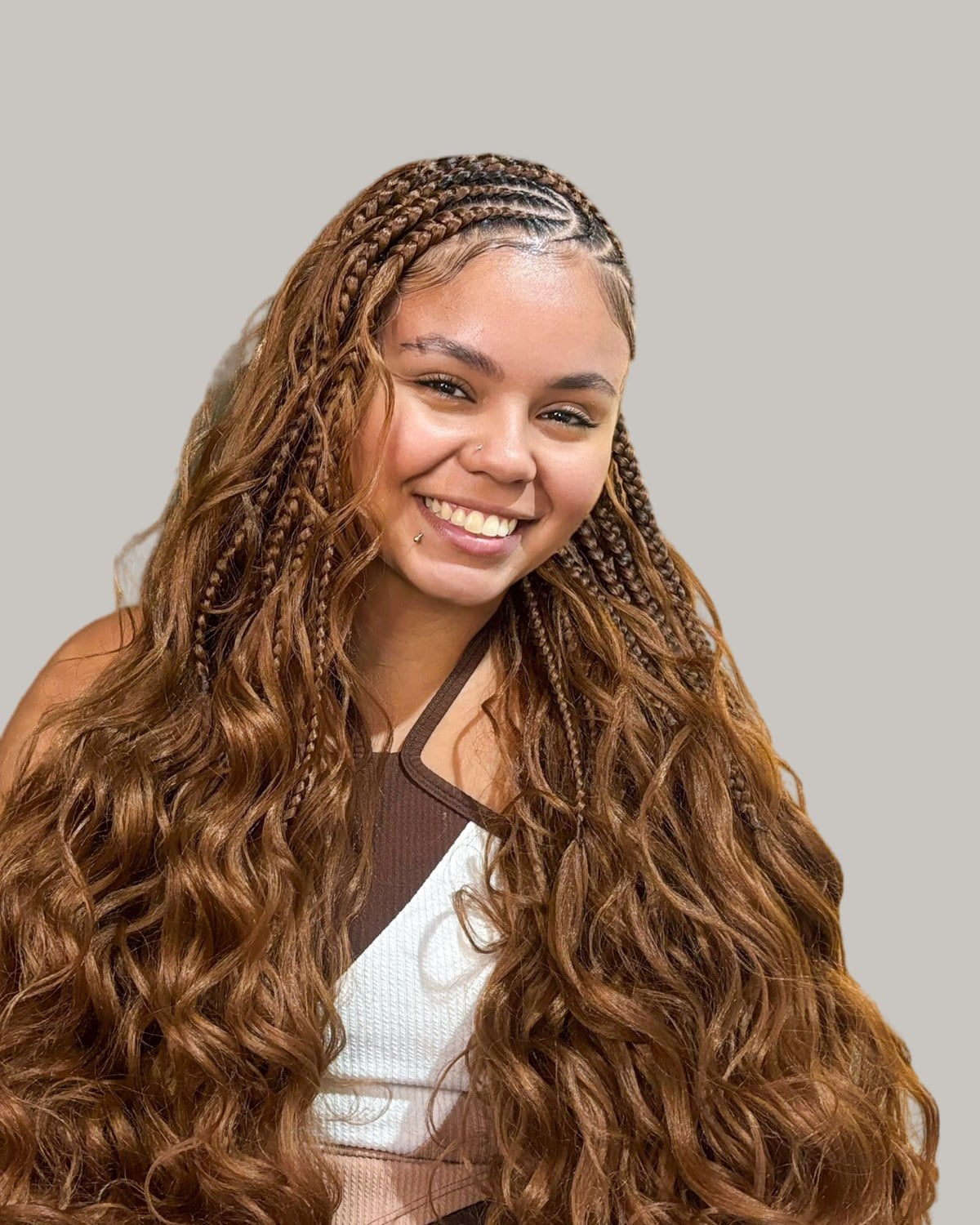 Smiling woman with side-swept Fulani rows and long copper French curl braids