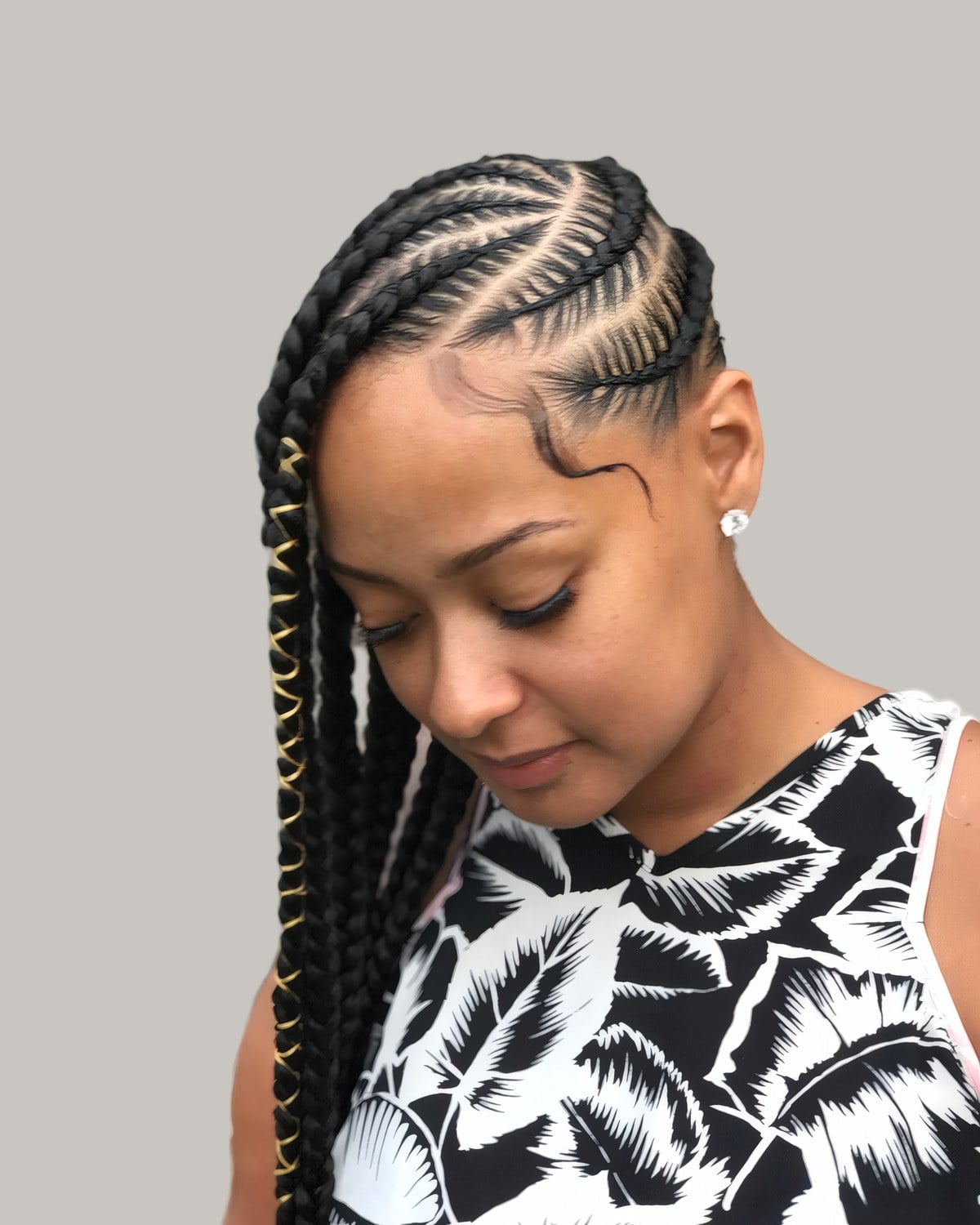 Woman in a black and white print top with lemonade Fulani braids and gold thread