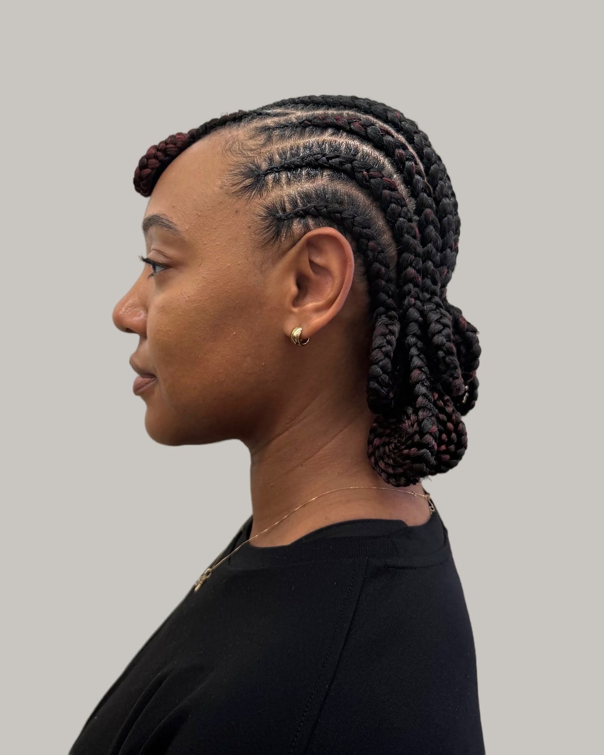 Woman in a black T-shirt in profile with curved Fulani rows and low buns