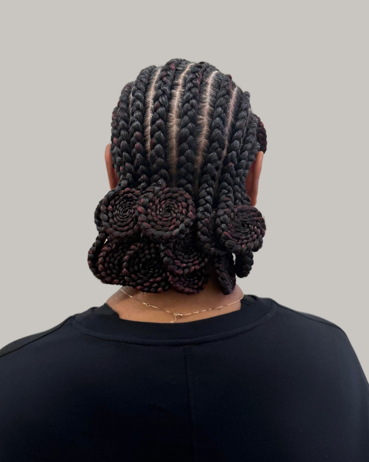 Back view of Fulani braids coiled into low buns over a black T-shirt