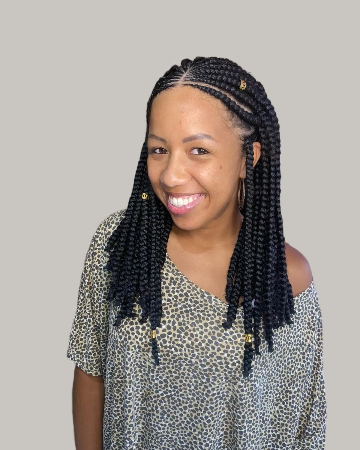 Smiling woman in a leopard-print top with medium black Fulani braids to the chest