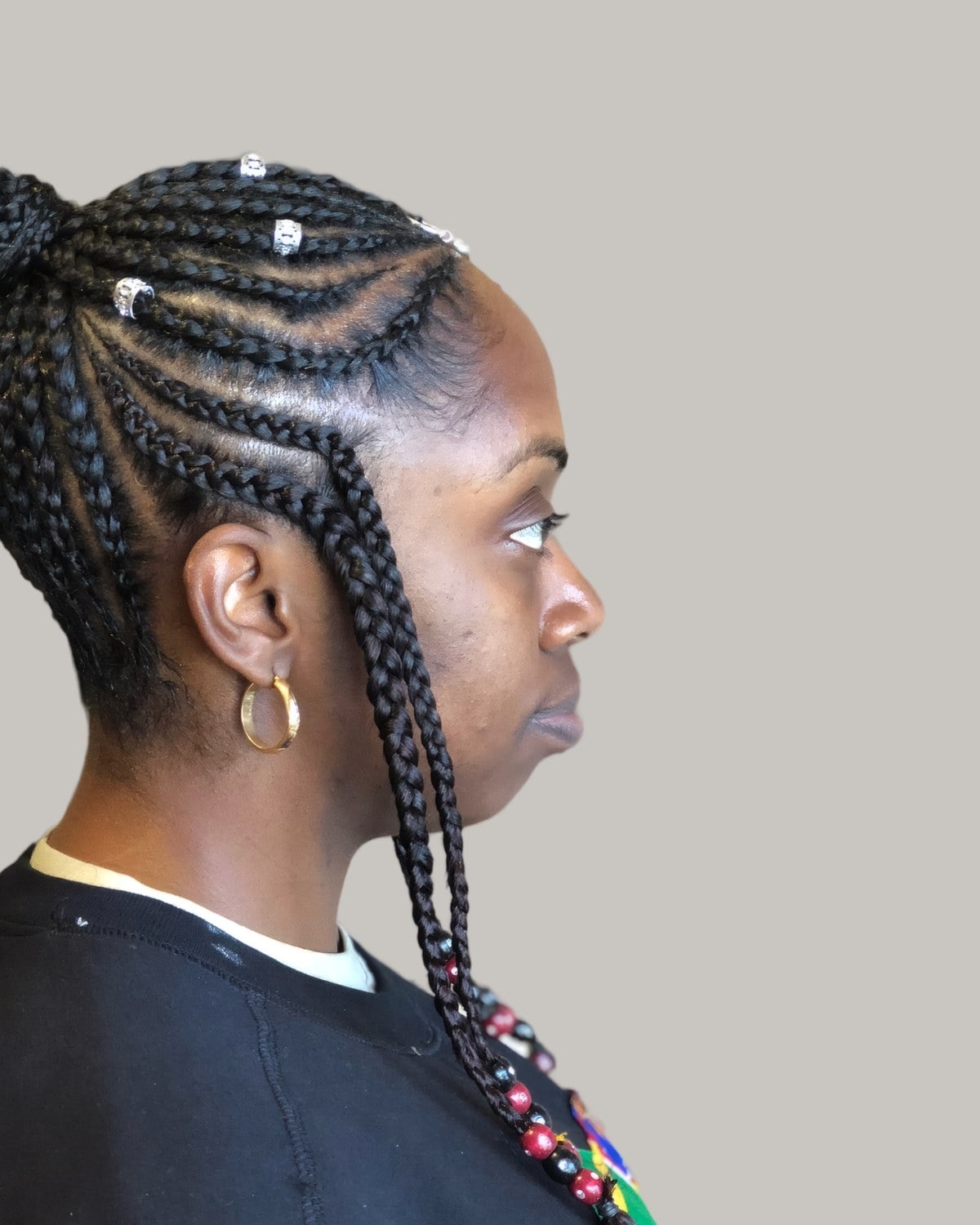 Woman in a black top seen in profile with Fulani rows pulled into a high braided ponytail