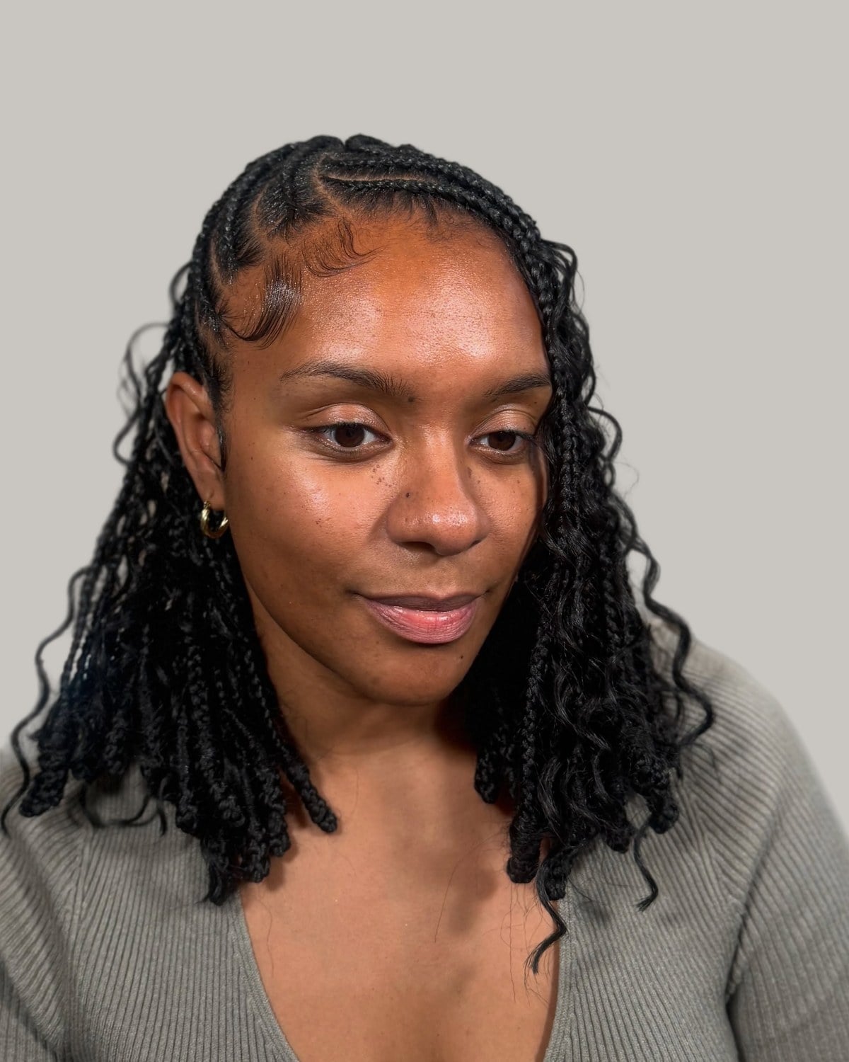 Woman in a gray sweater with short Fulani braids and curly ends