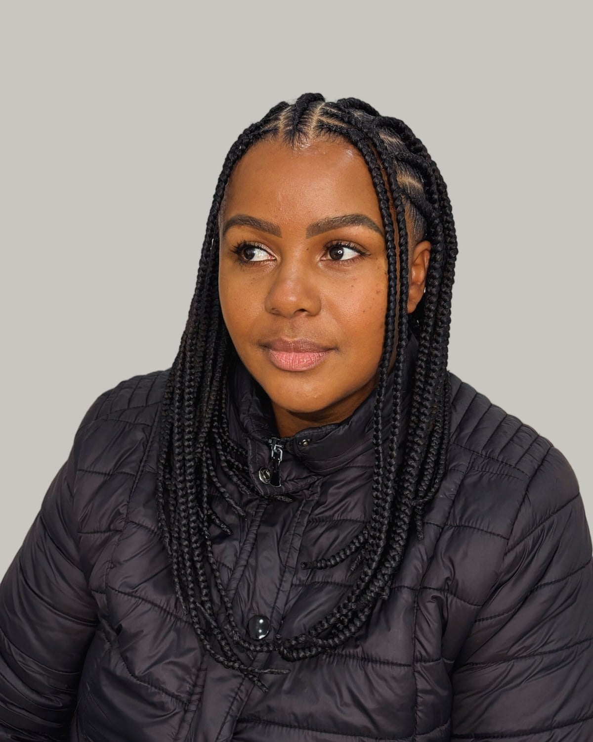 Woman in a black puffer jacket with black Fulani braids just past the shoulders