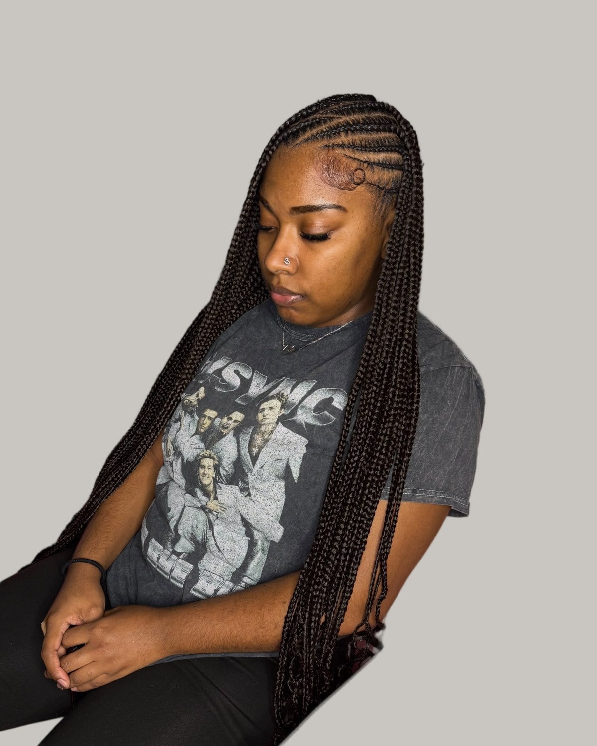 Woman in a gray graphic T-shirt with side-part Fulani braids past the waist