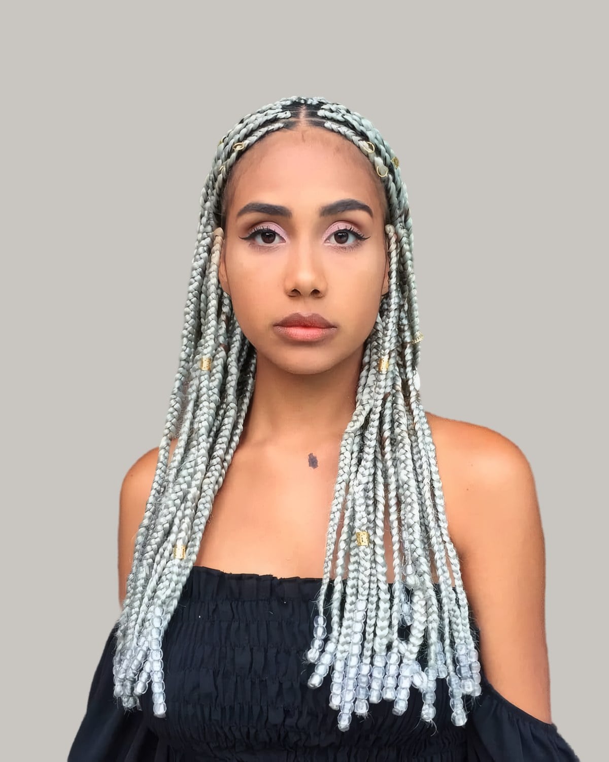 Woman in a black off-shoulder top with silver-gray Fulani braids from a center part