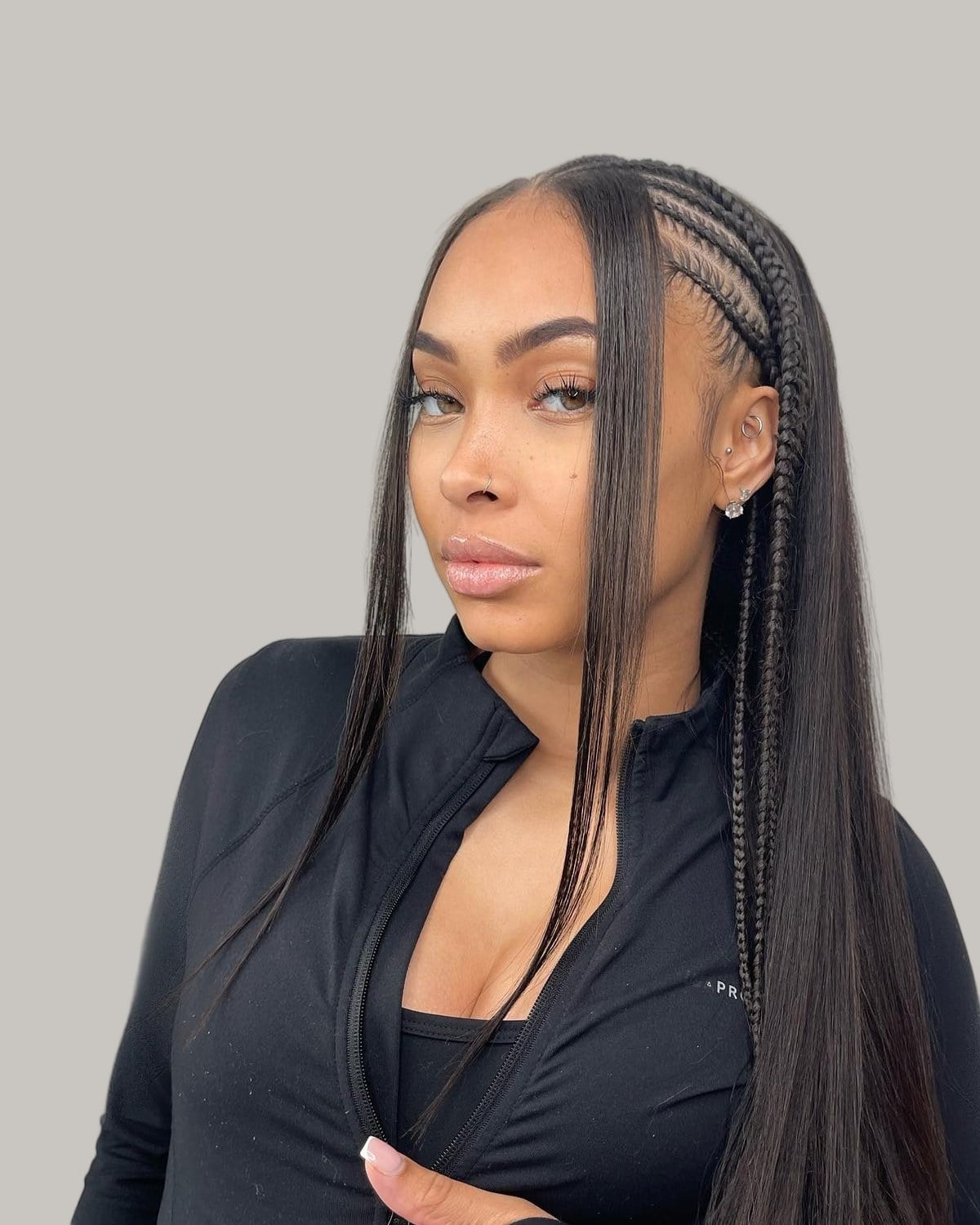 Woman in a black zip top with cornrows on one side and long straight hair