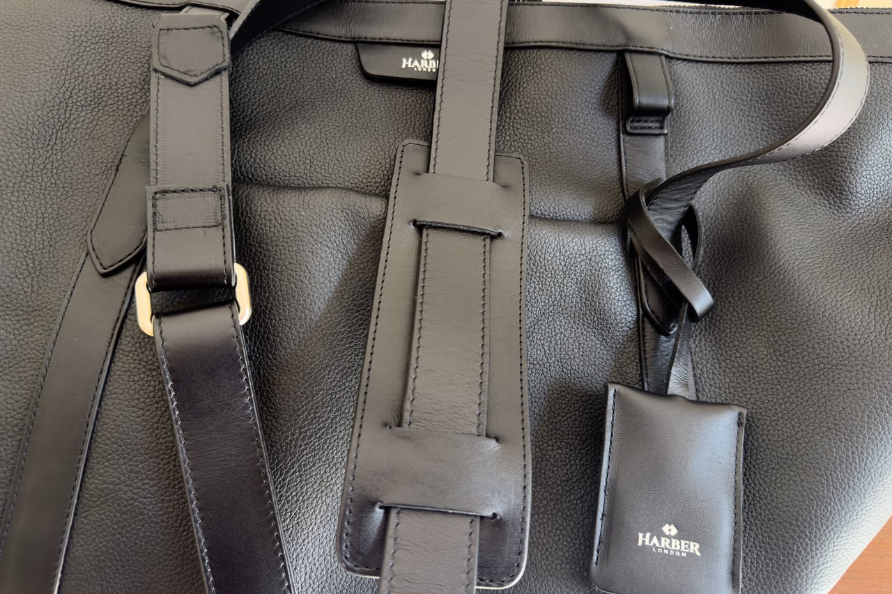Shoulder strap pad, handles and AirTag holder against the pebbled leather front of the Harber London Leather Overnight Bag - Luxe Digital