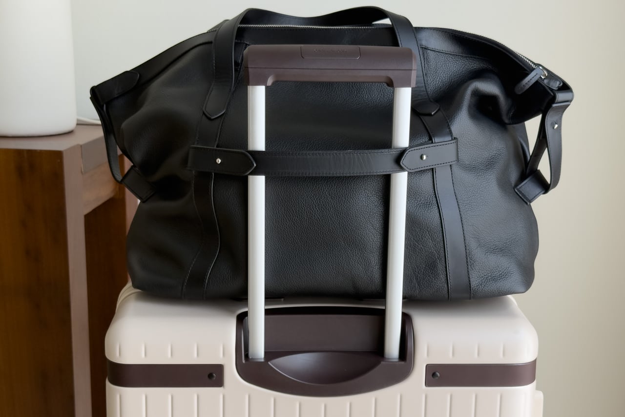 Harber London Leather Overnight Bag stacked on a suitcase with its rear luggage sleeve over the trolley handle - Luxe Digital