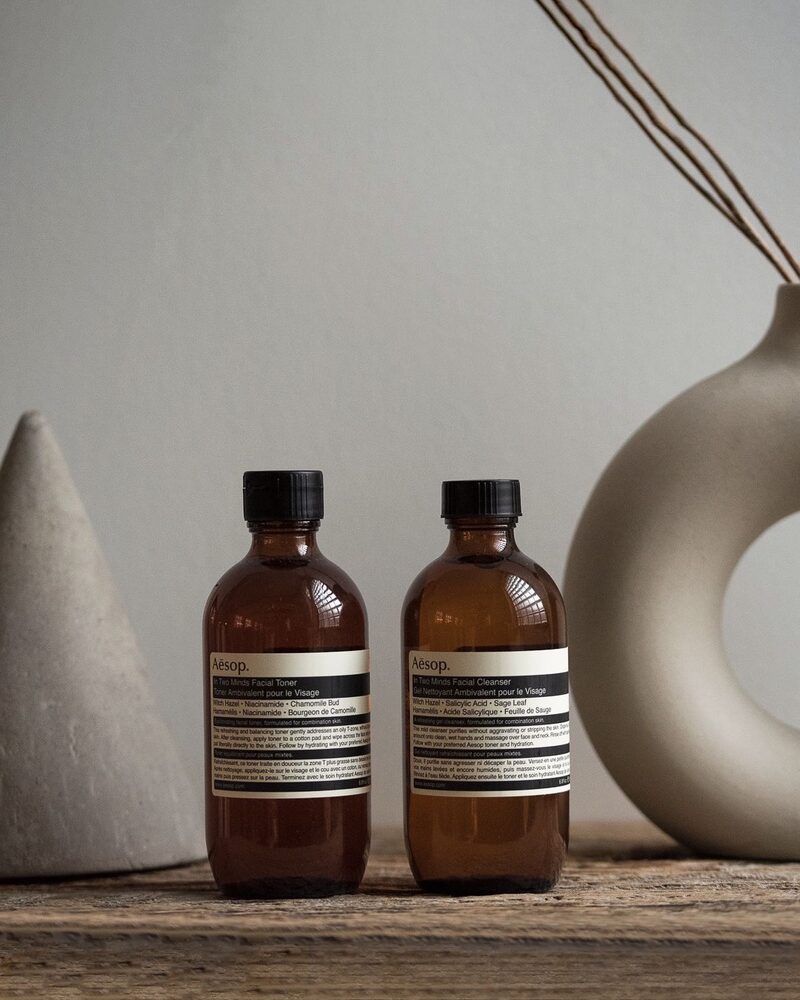 Amber glass skincare bottles styled with a ceramic vase on a wooden surface