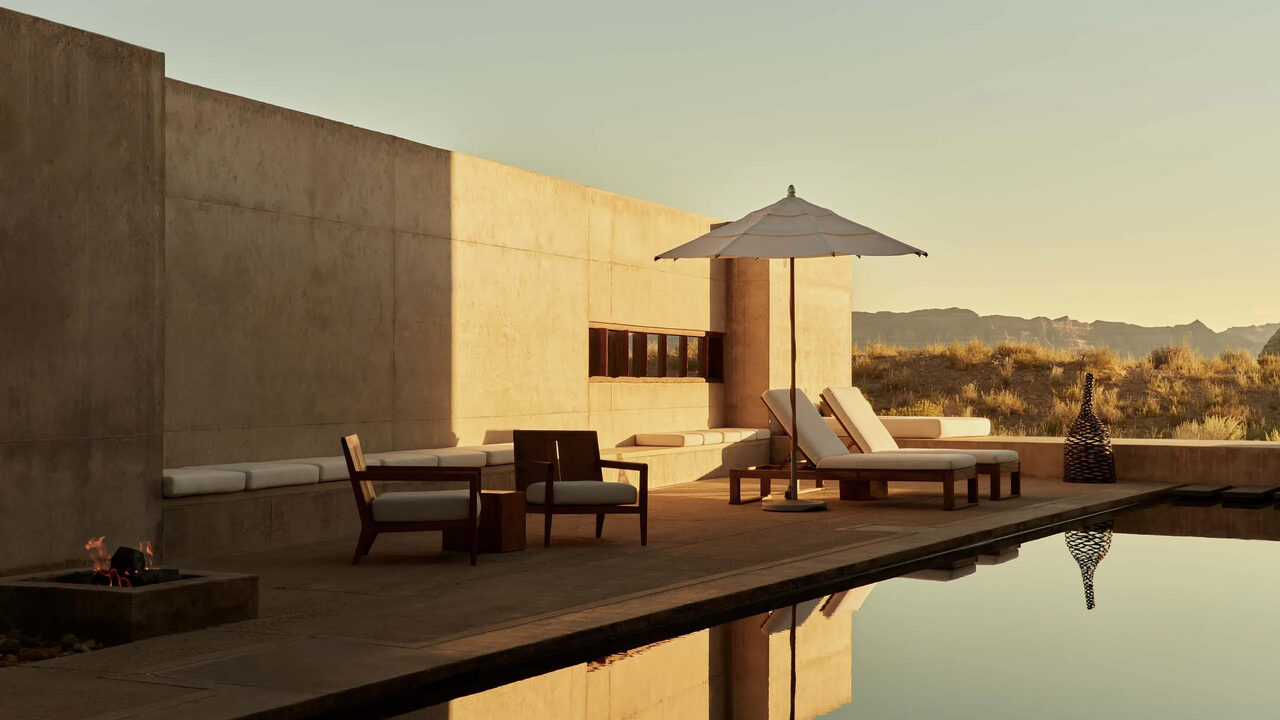 An Amangiri pool terrace with loungers at golden hour in the desert