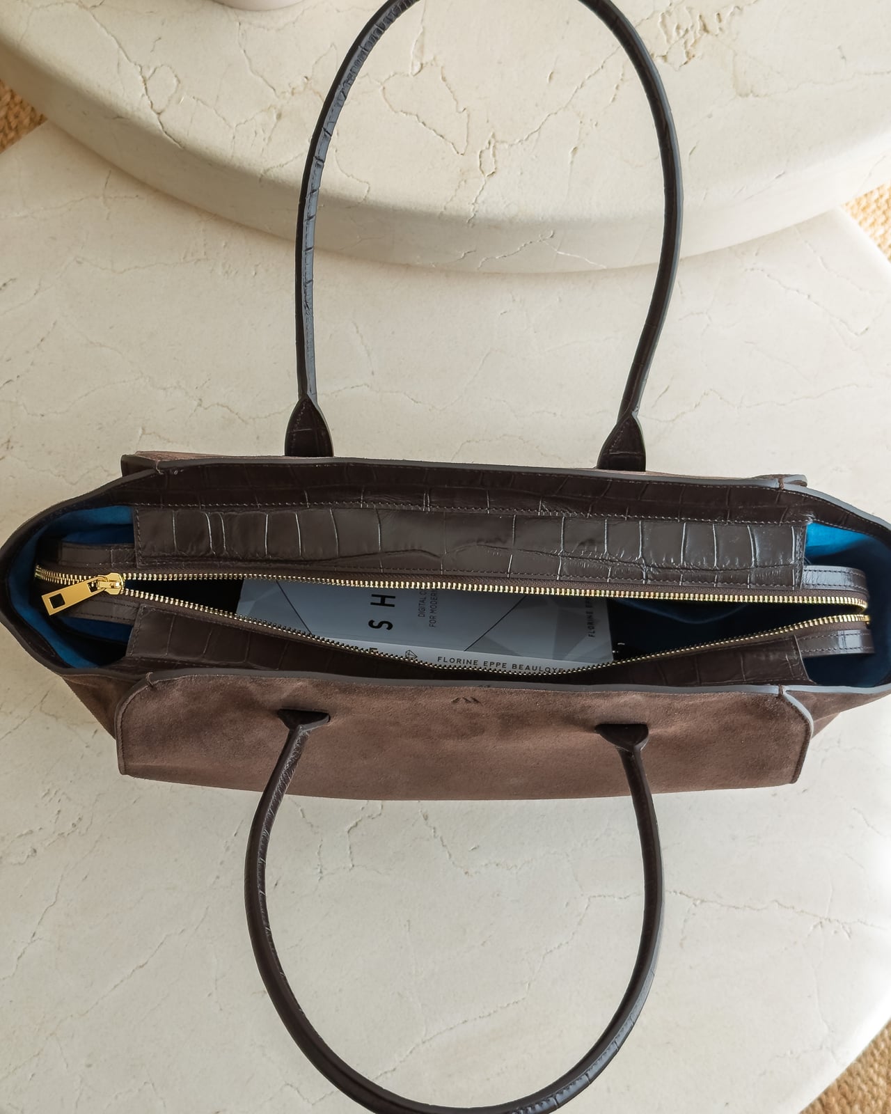 Top view of the KAAI Voyager suede tote with its zip half open - Luxe Digital
