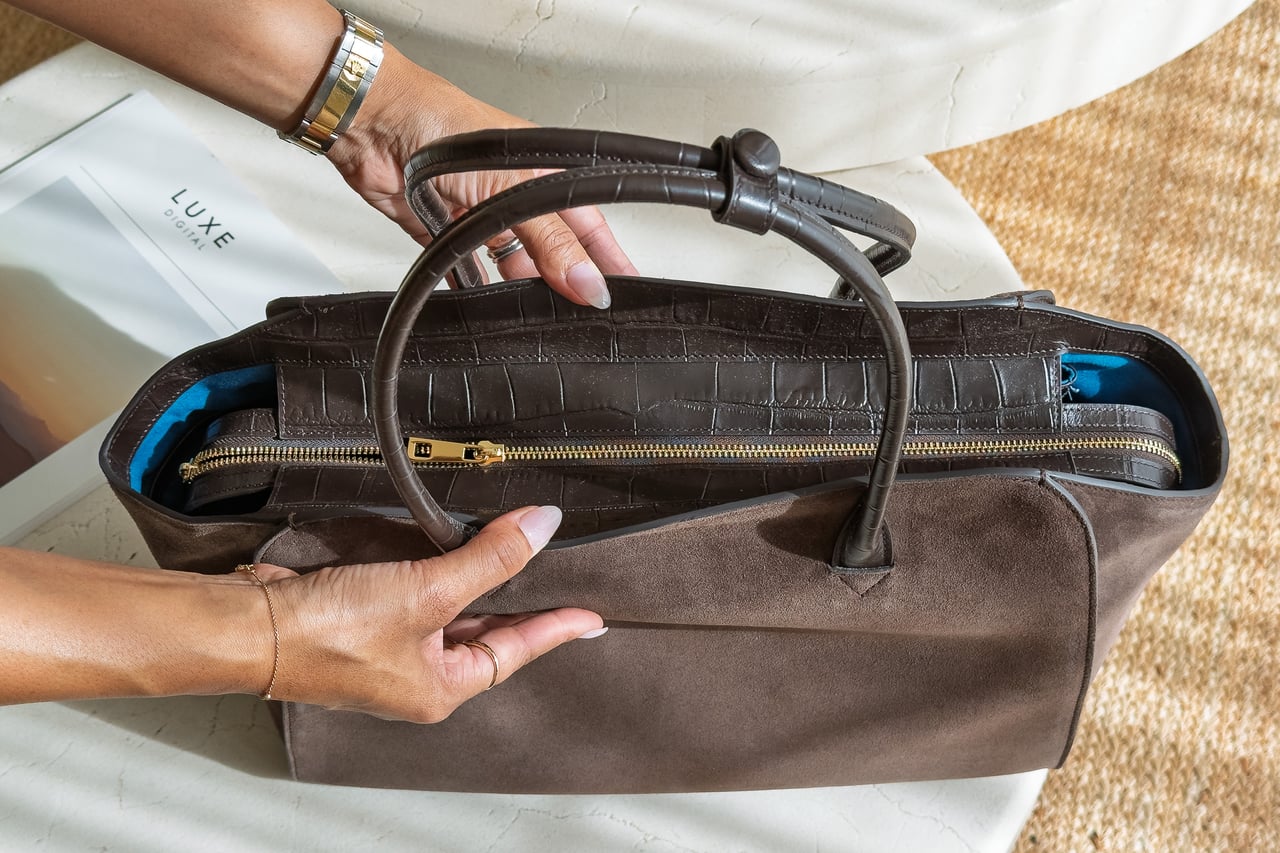 Two hands unzipping the full-width zip across the top of the KAAI Voyager - Luxe Digital