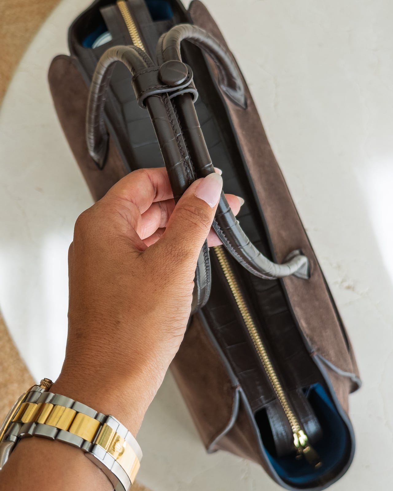 Hand holding the rolled leather handles of the KAAI Voyager from above - Luxe Digital