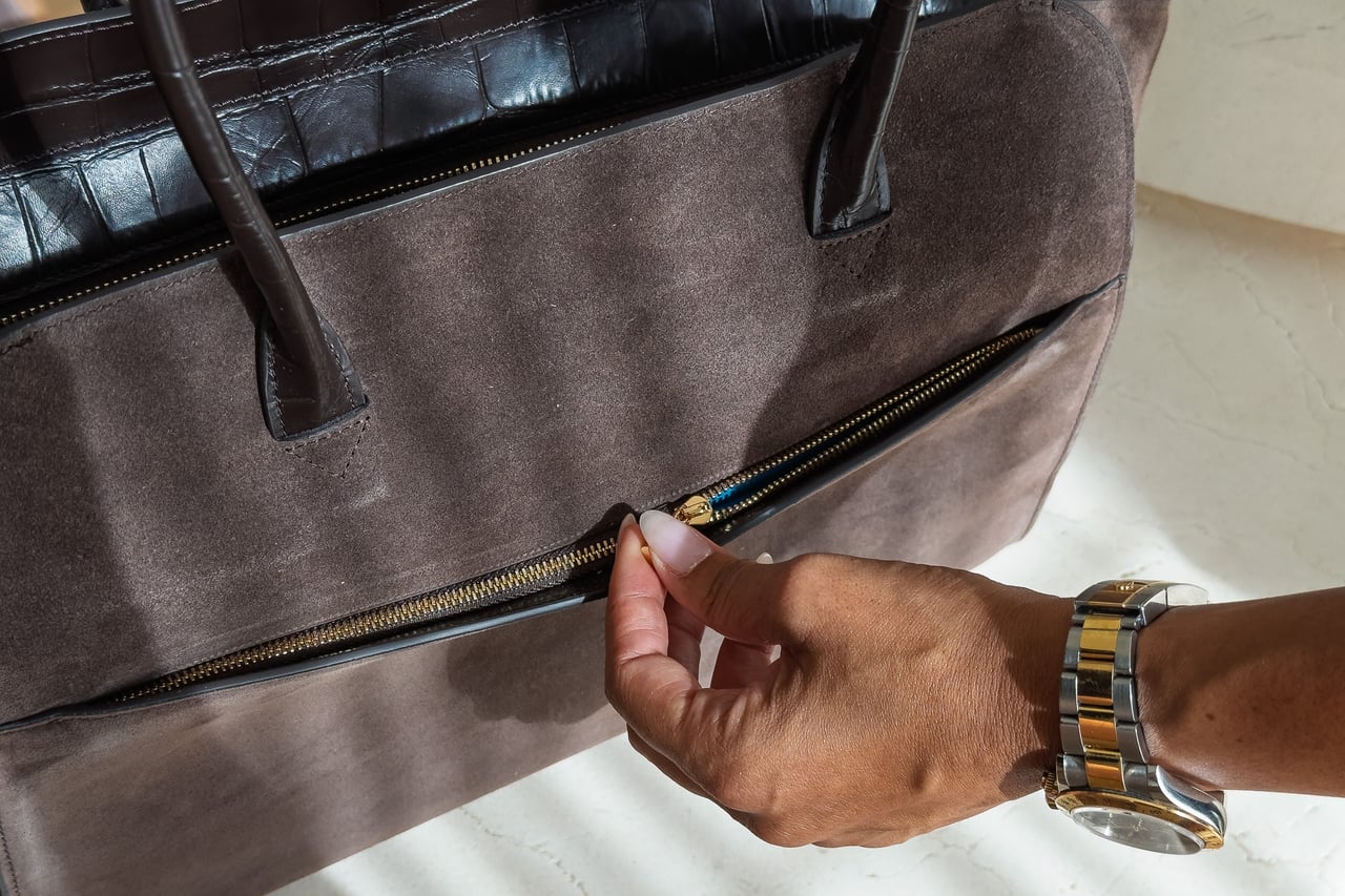 Hand unzipping the outer pocket on the suede side of the KAAI Voyager - Luxe Digital