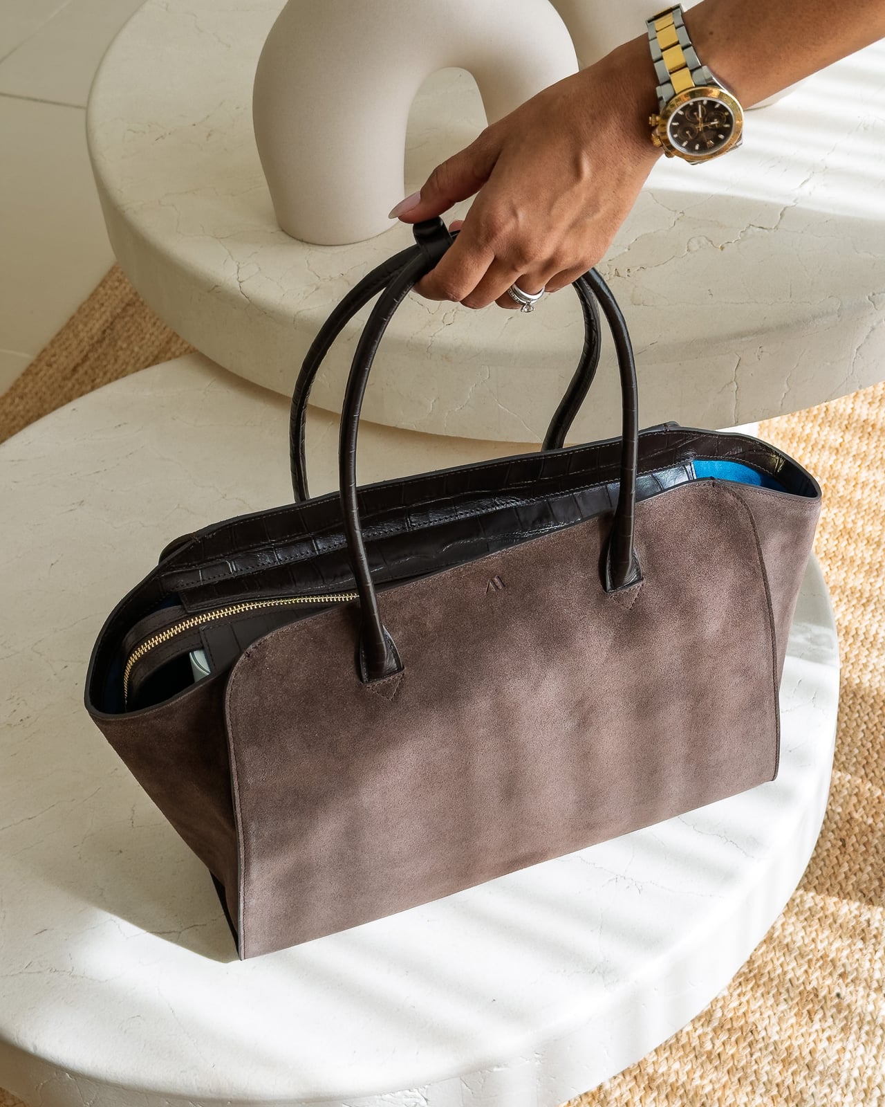 KAAI Voyager in Suede Espresso carried by its top handles - Luxe Digital