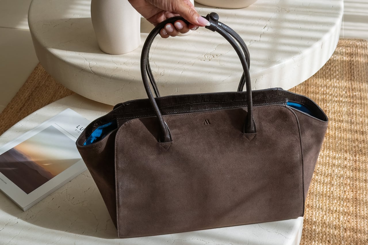 KAAI Voyager work bag in Suede Espresso held by its top handles - Luxe Digital