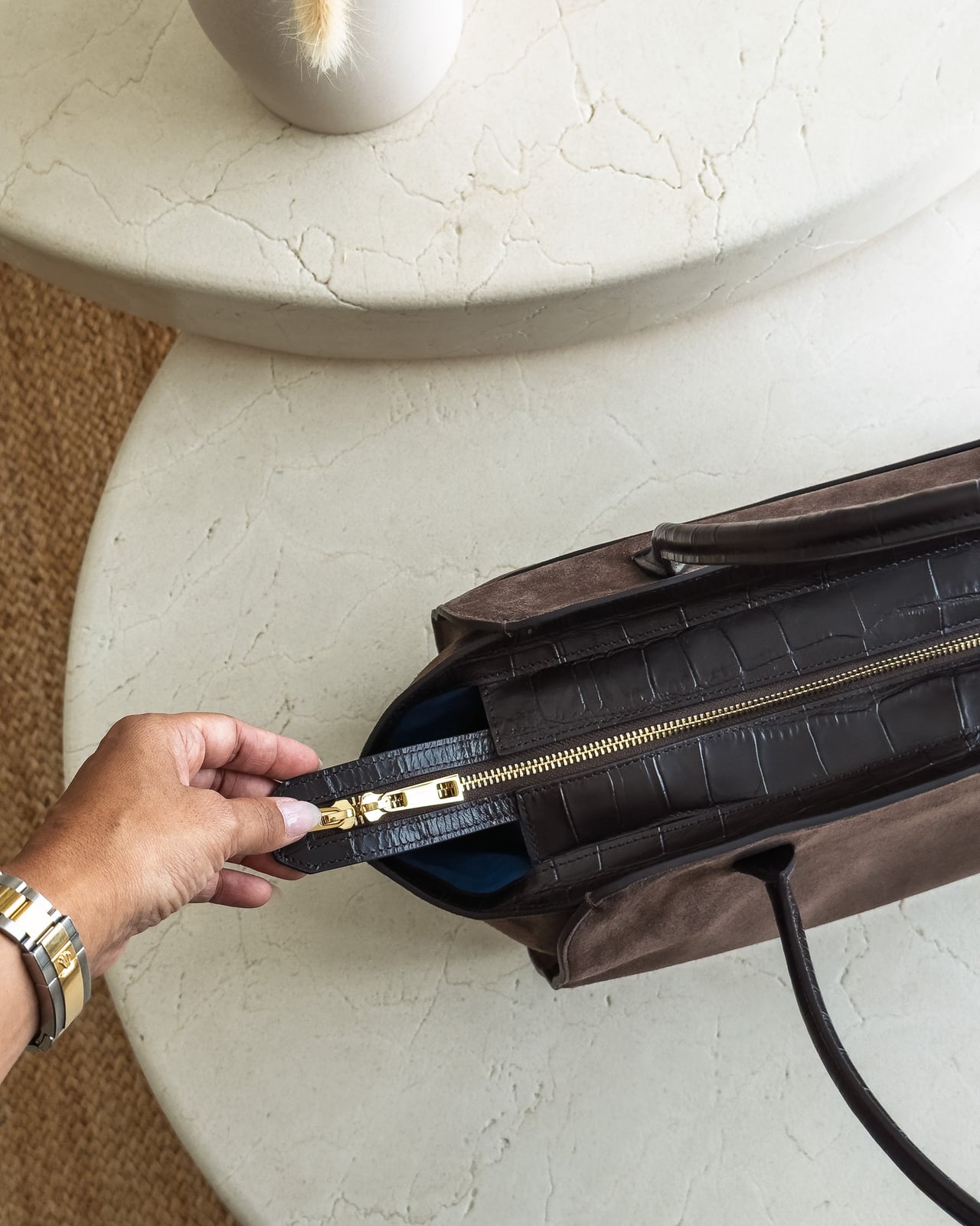 Hand on the gold-tone zip pull at the end of the KAAI Voyager - Luxe Digital
