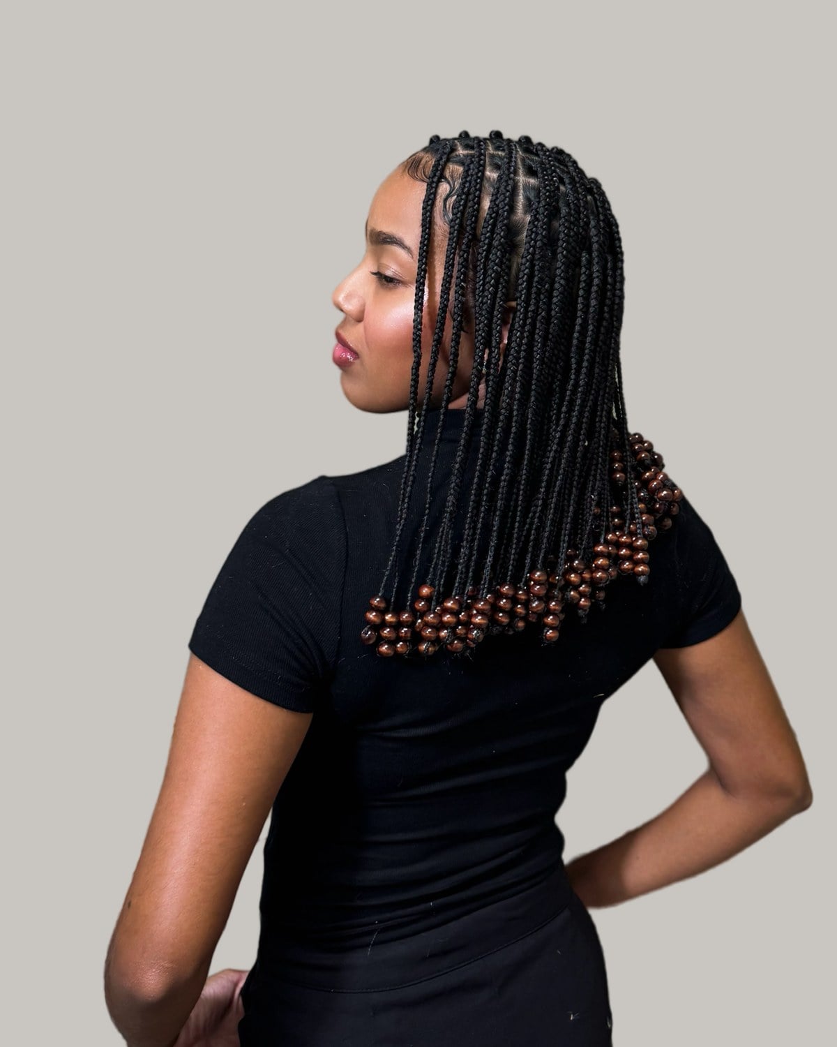 Woman in a black T-shirt seen from behind, black knotless lob with wooden beads