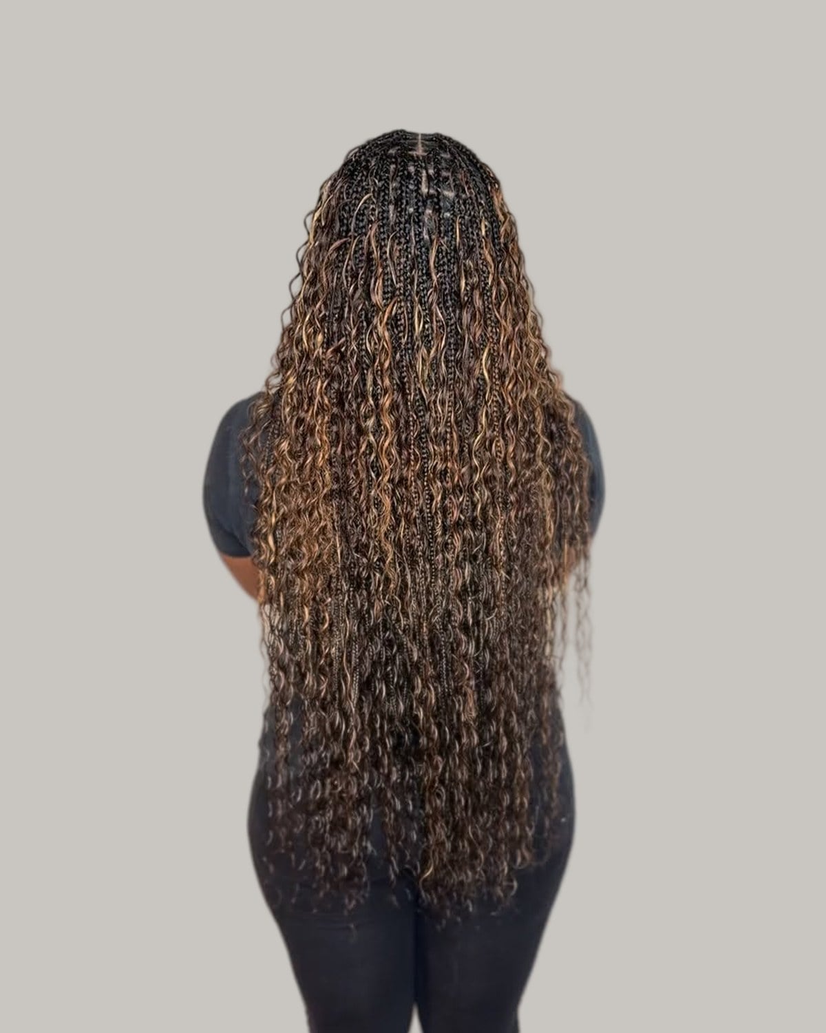 Back view of a woman with long medium boho knotless braids in black and honey brown, curls left out along each braid