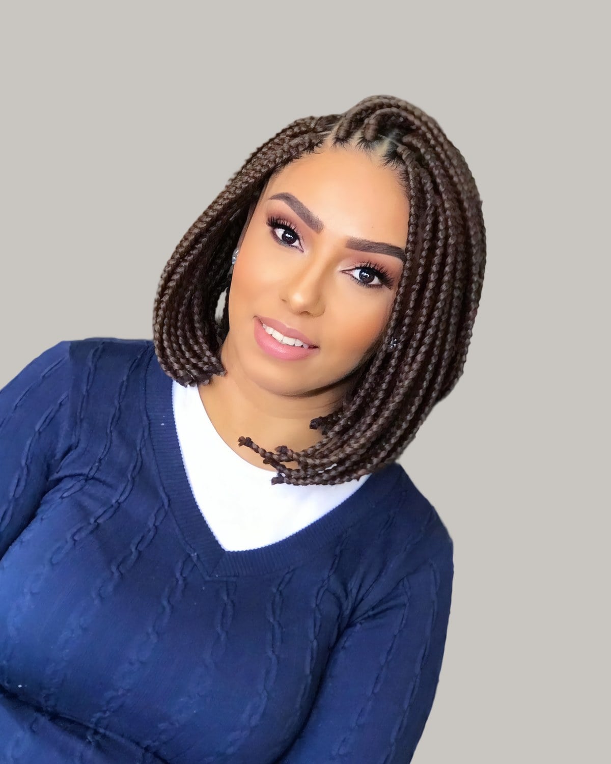 Smiling woman in a navy sweater with a brown knotless braid bob