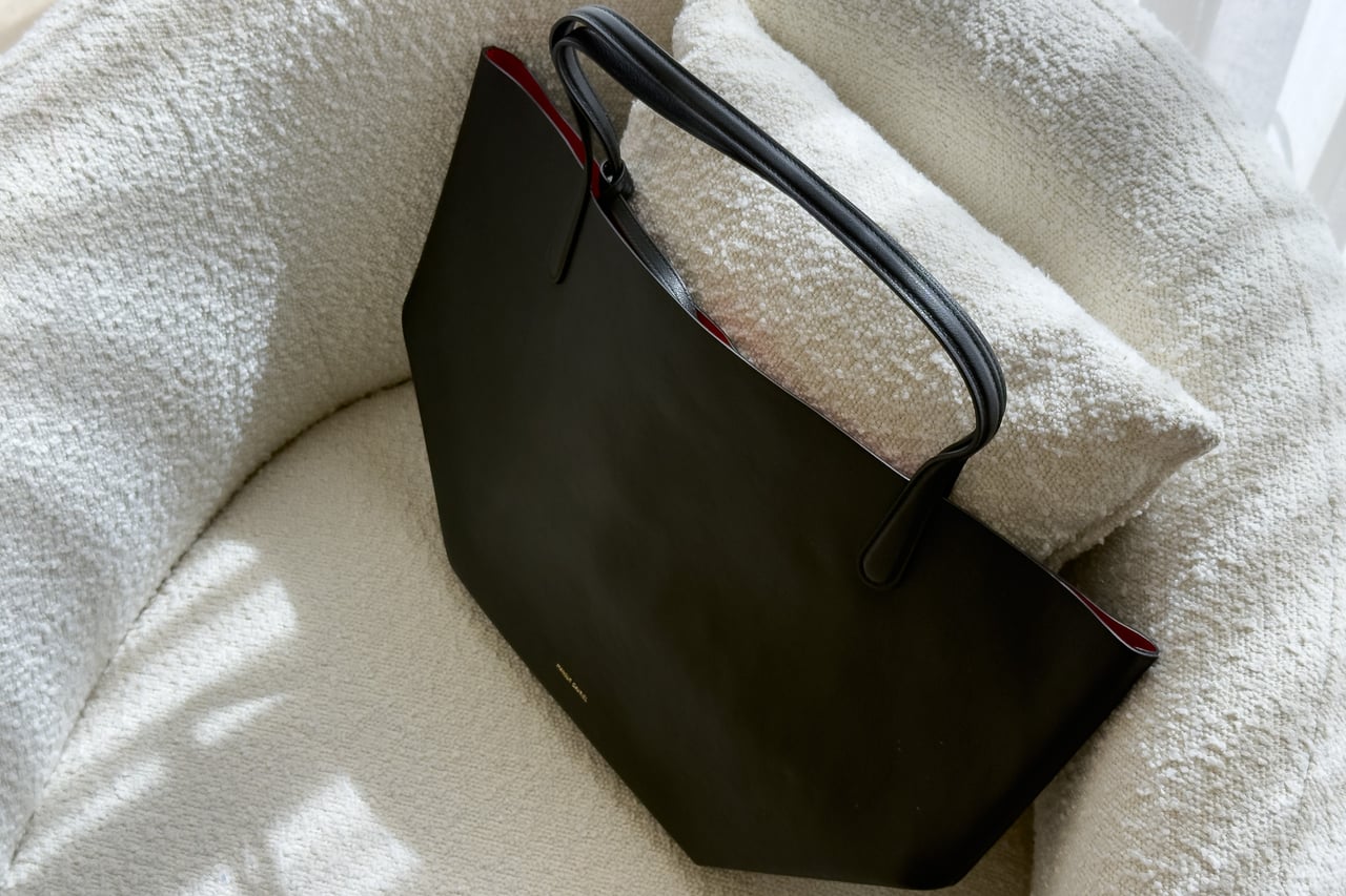 Black Mansur Gavriel Everyday Soft Tote lying on a cream armchair - Luxe Digital