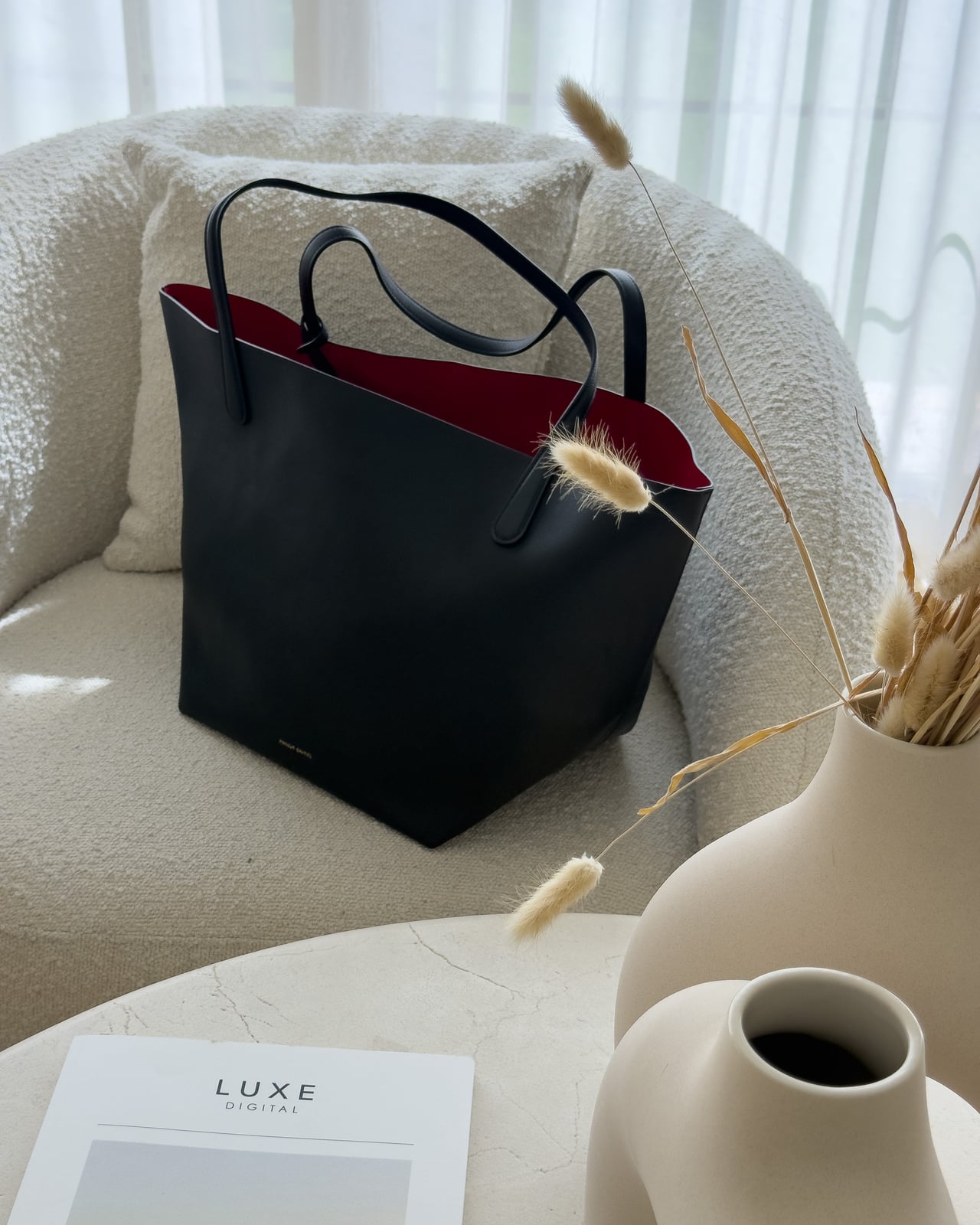 Mansur Gavriel Everyday Soft Tote in Black/Flamma on an armchair beside a Luxe Digital print - Luxe Digital