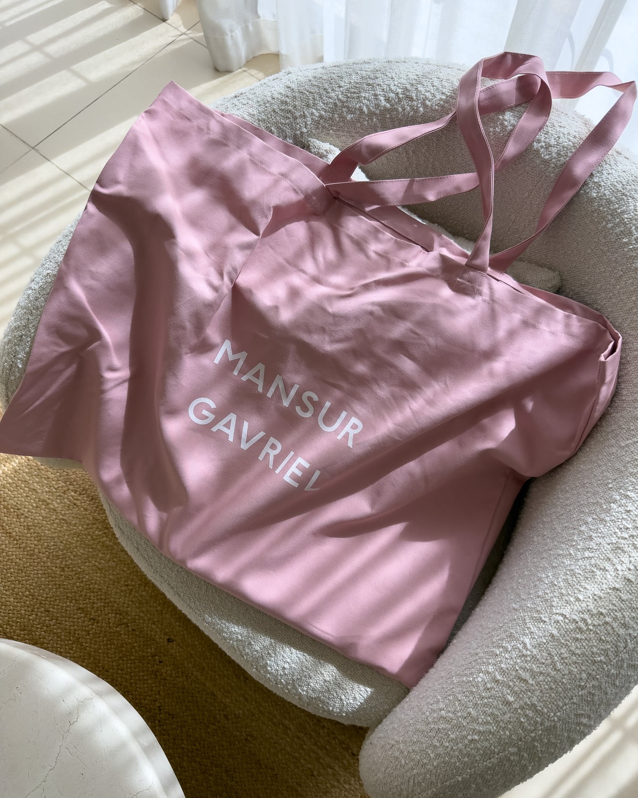 Pink Mansur Gavriel dust bag on a cream armchair - Luxe Digital