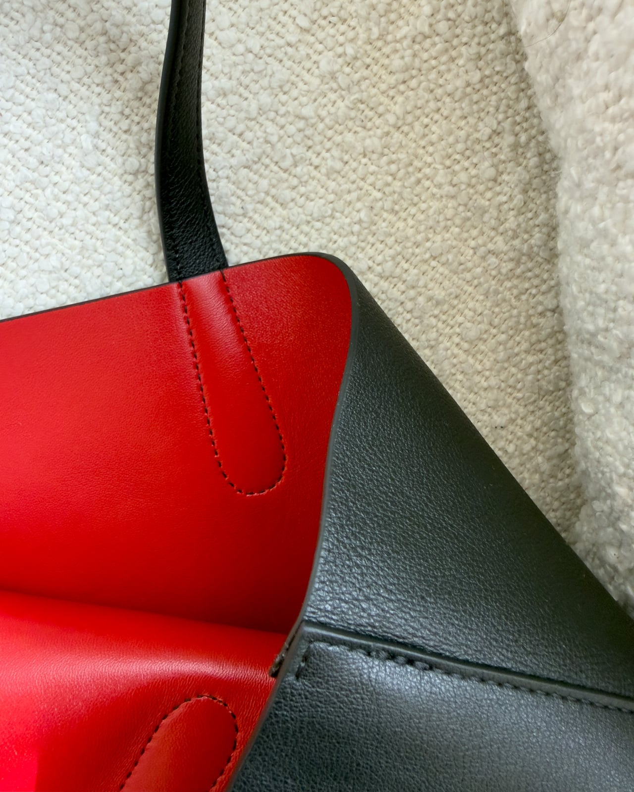 Close-up of the black calfskin exterior meeting the red lambskin lining at the top edge of the tote - Luxe Digital