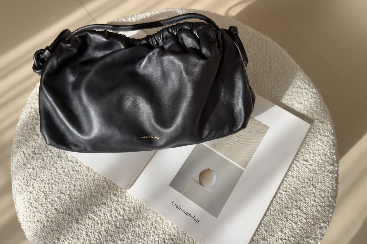 Mansur Gavriel Oversized Cloud Clutch in Black/Flamma on a round stool - Luxe Digital