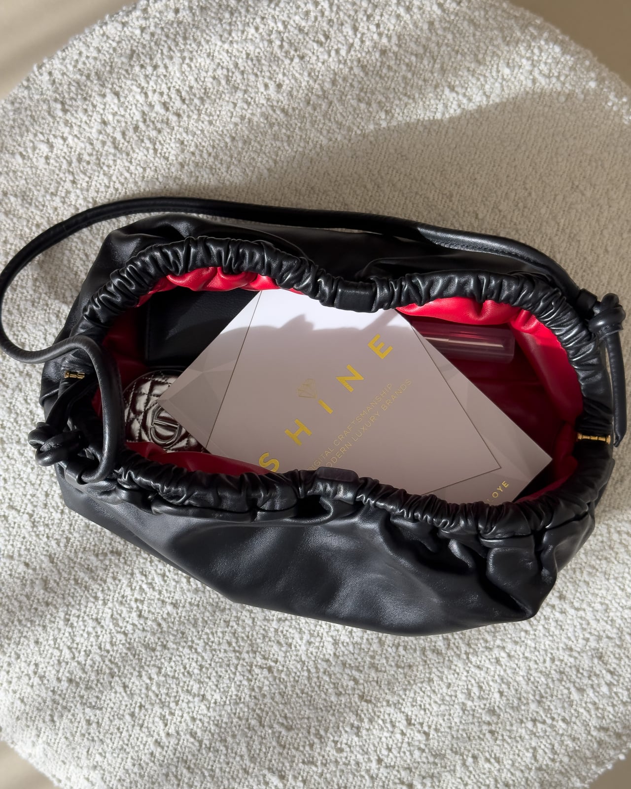 Top view into the open Mansur Gavriel Oversized Cloud packed with a book, a compact and a wallet - Luxe Digital