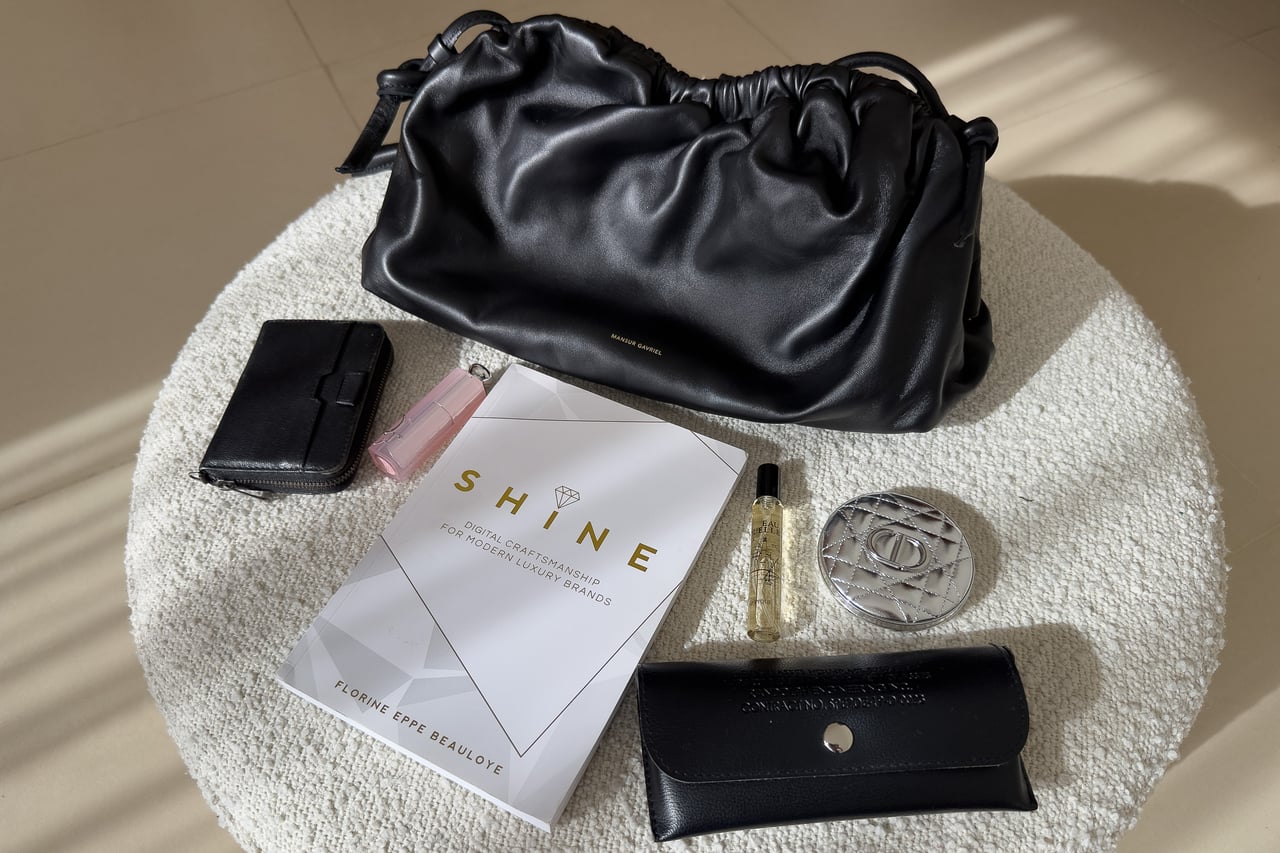 Mansur Gavriel Oversized Cloud beside a wallet, a sunglasses case, a book, perfume, lip gloss and a compact - Luxe Digital