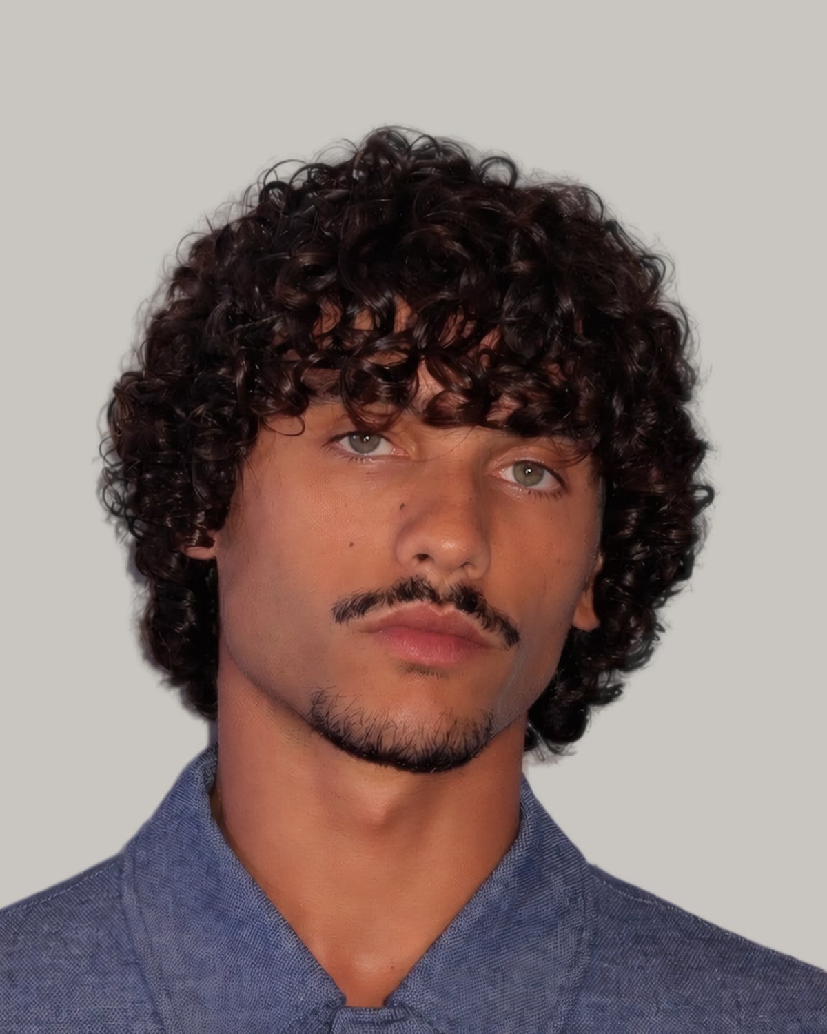 Man with a mustache and a round crop of dark curls, seen from the front