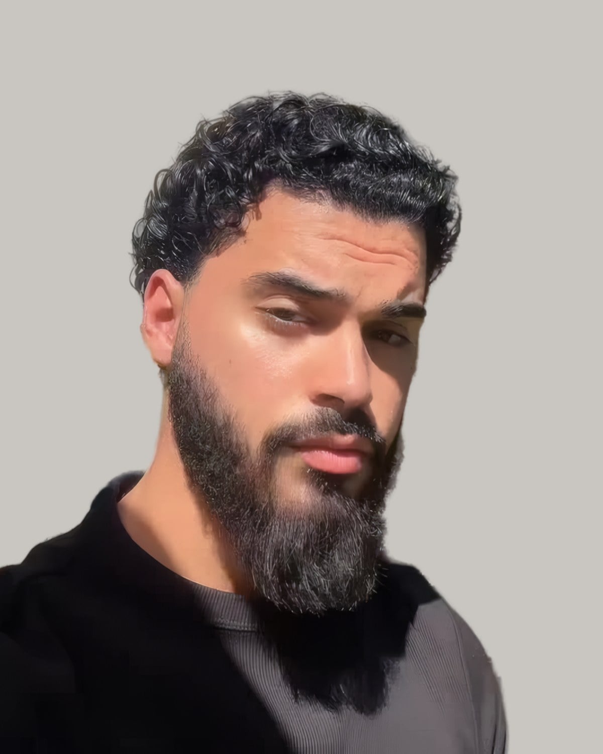 Bearded man with curly hair swept back, seen from the front