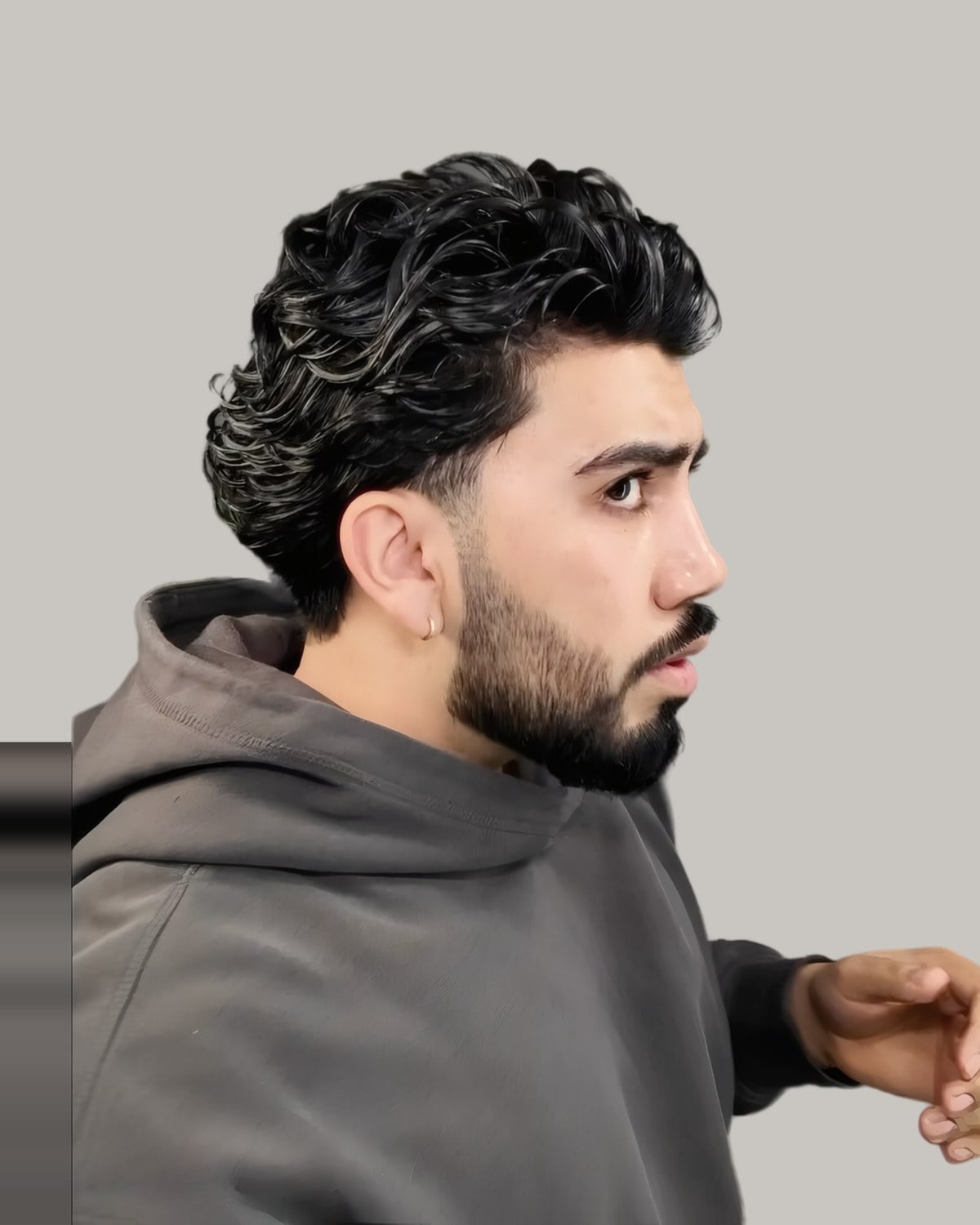 Bearded man with dark wavy hair and tapered sides, seen from the side