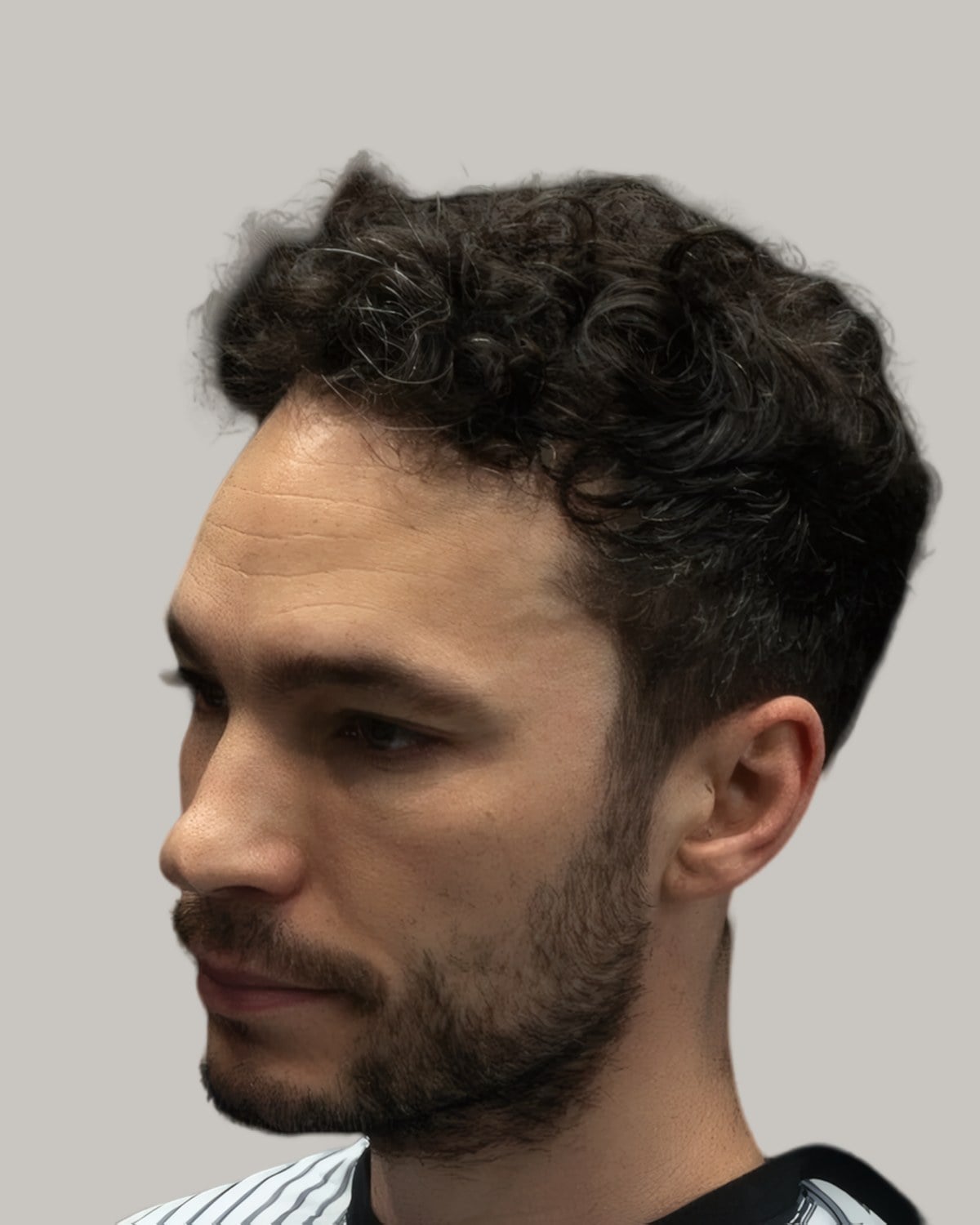 Bearded man with short curls and a taper, seen from the side