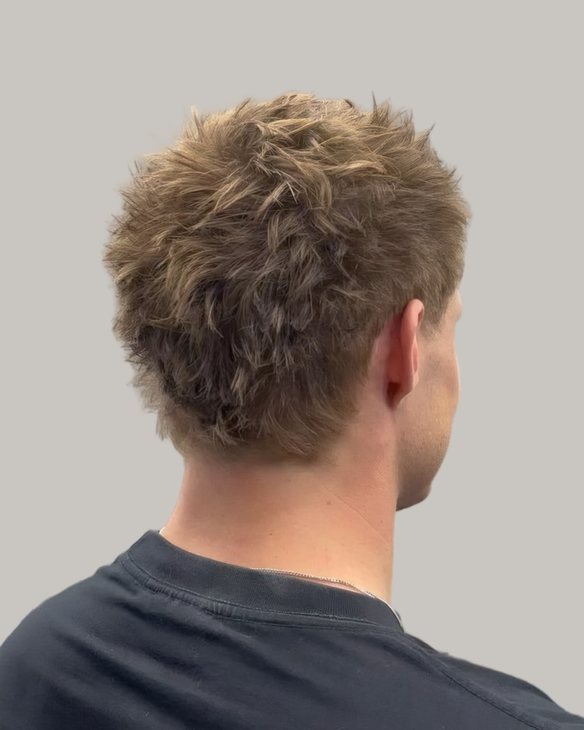 Man with a short textured top and a tapered neckline, seen from behind