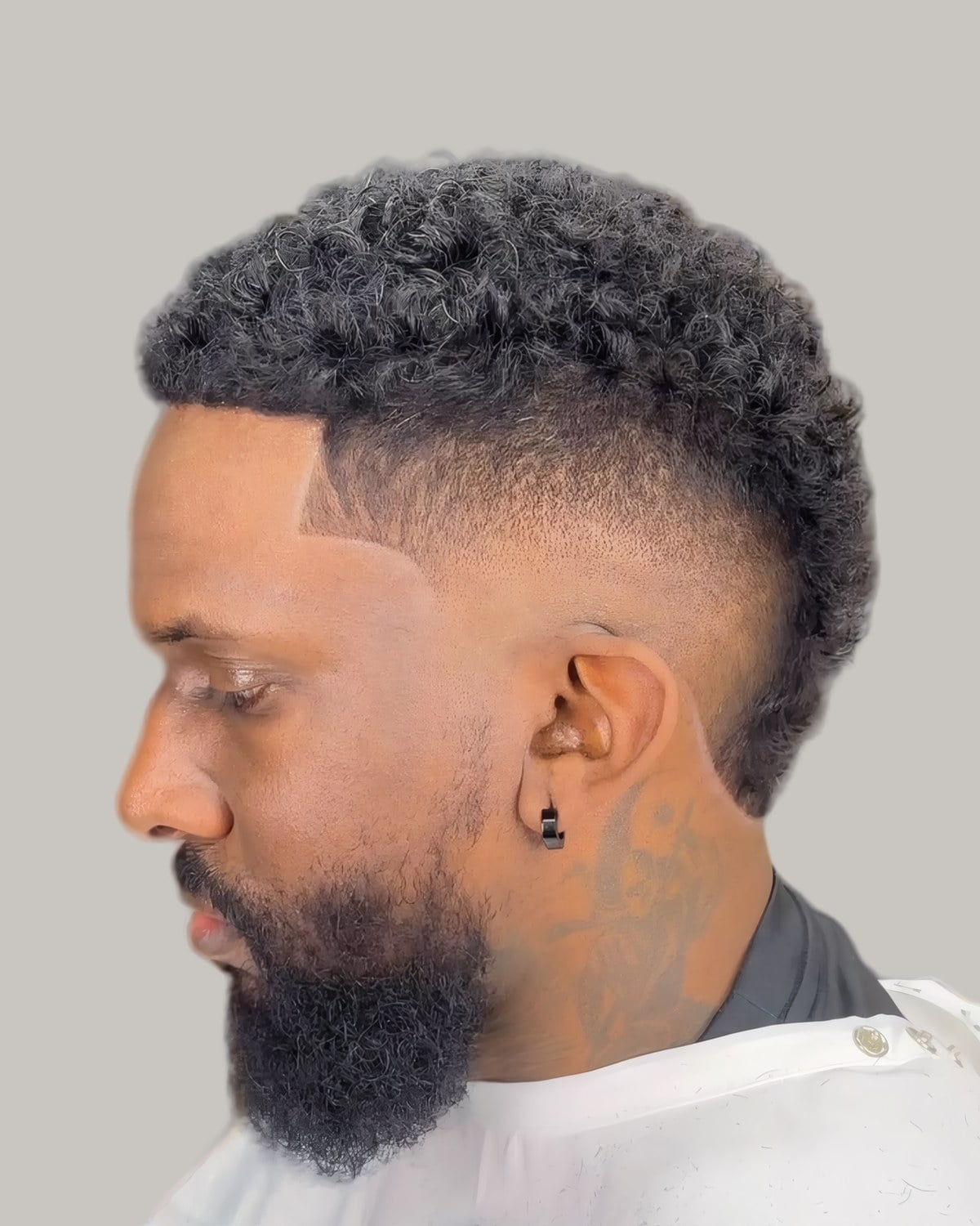 Bearded man with short curls and a fade, seen in profile