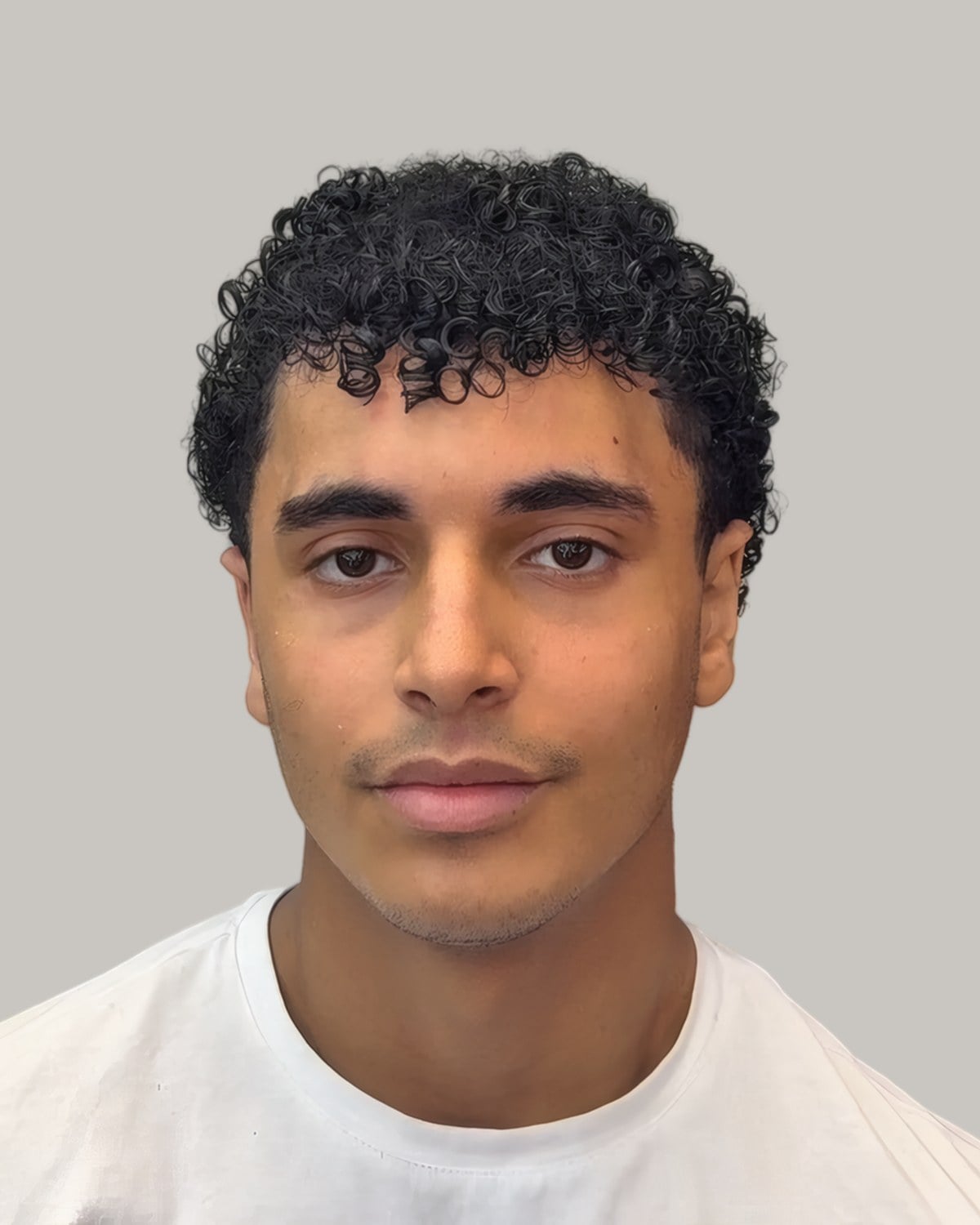 Young man with a short curly fringe and short sides, seen from the front