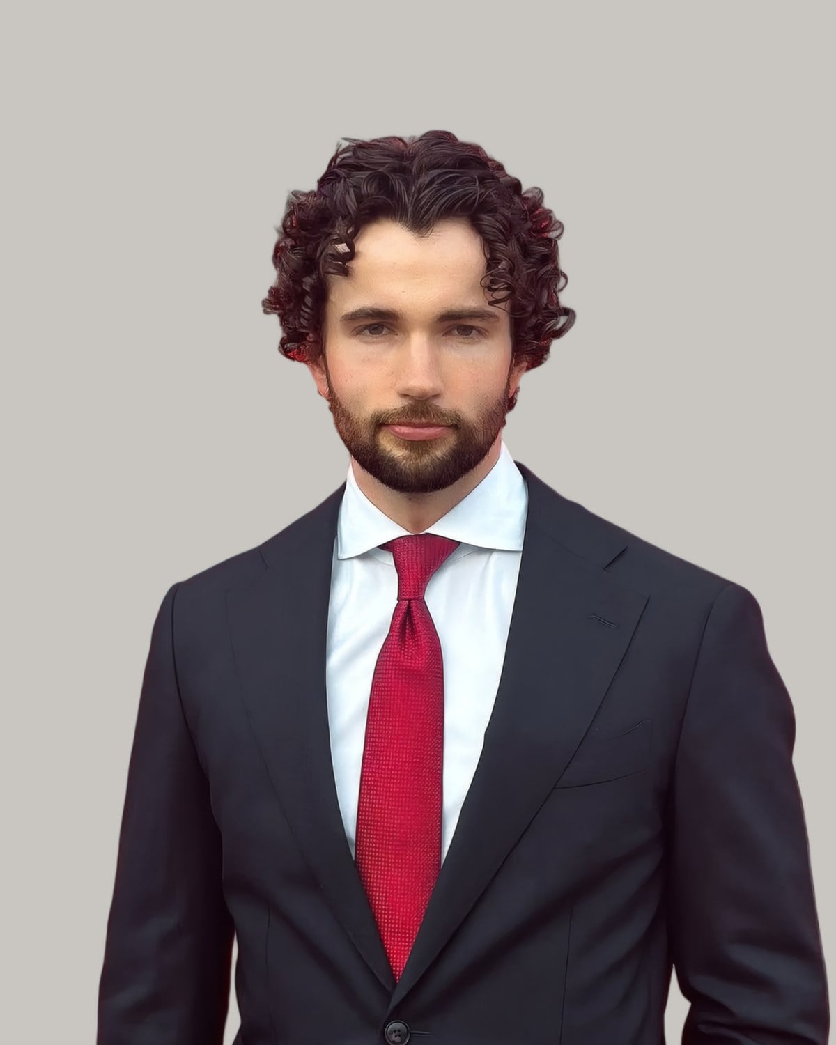 Man with dark curls in a suit and red tie, seen from the front