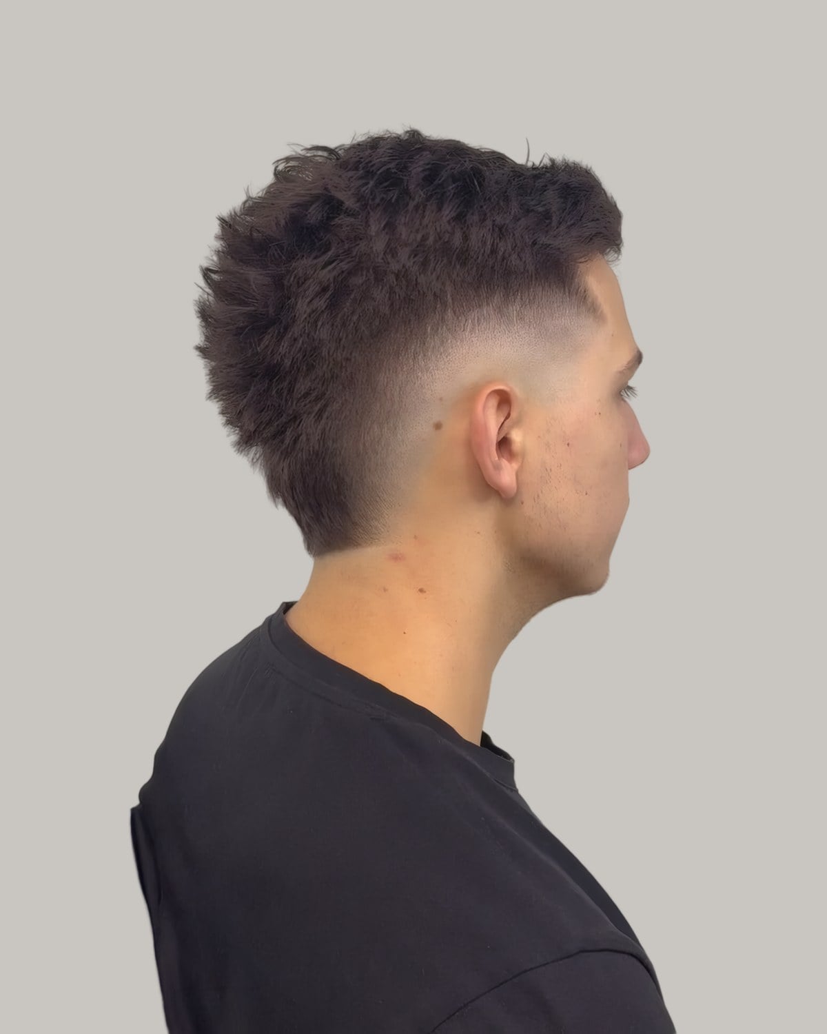 Man with a short textured crop and a taper, seen from behind at an angle