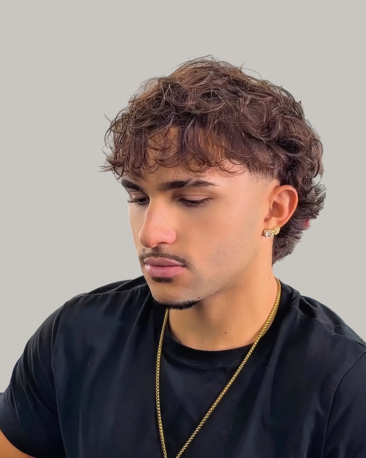 Young man with a curly top and a low taper, seen from the front at an angle