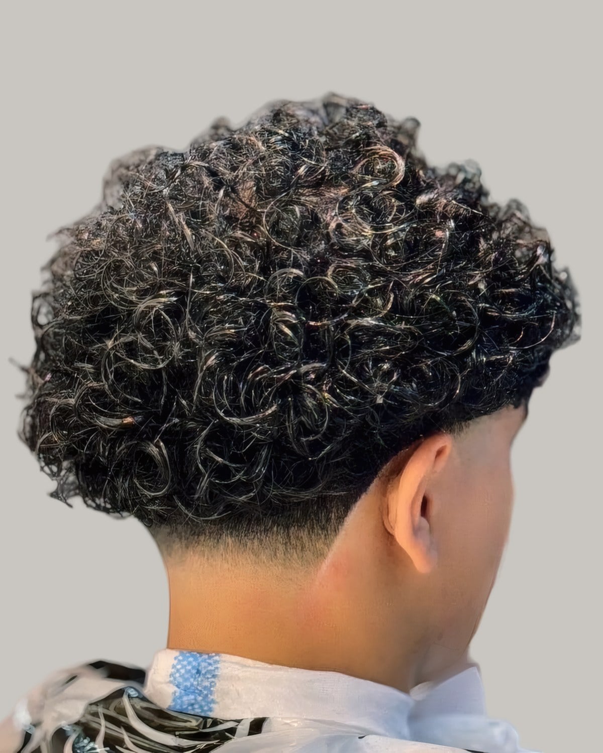 Man with dense curls and a short neckline, seen from behind