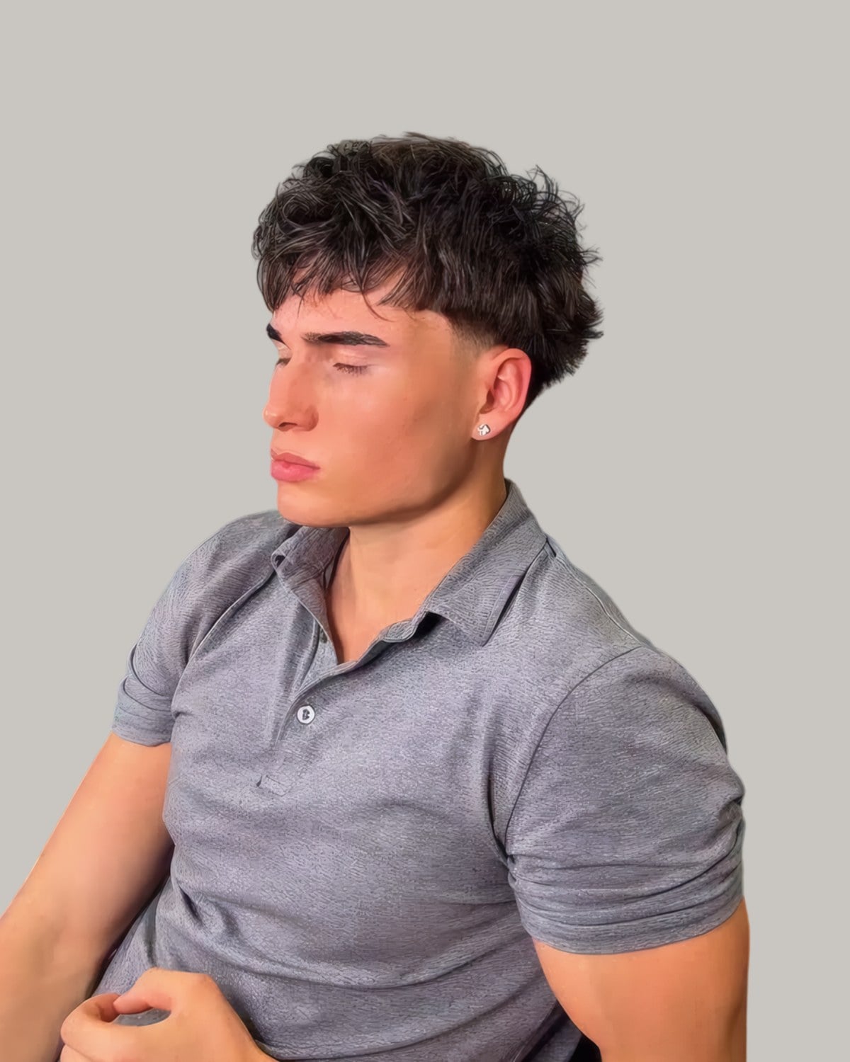 Young man with short curls and a neat neckline, seen from the side