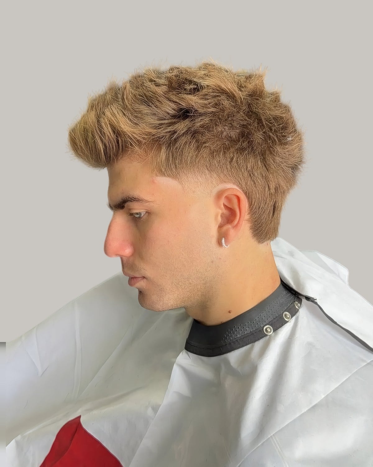 Man with light blonde curls and a taper, seen from the side